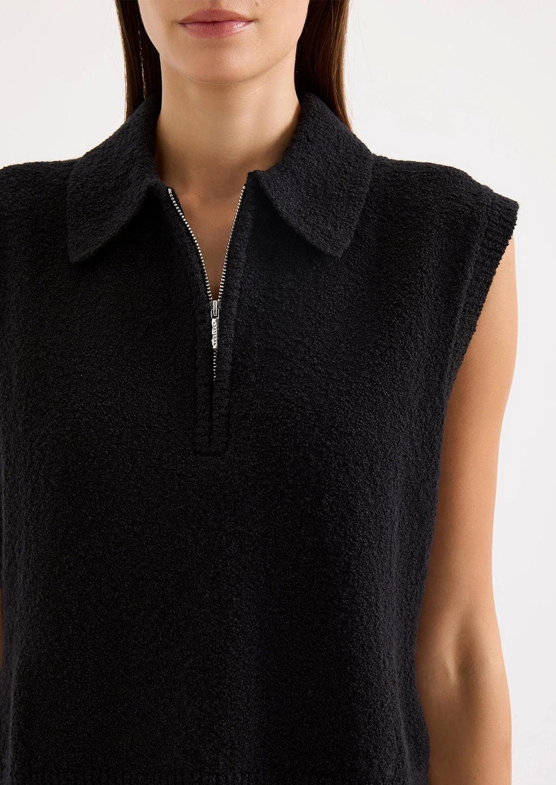 Black sleeveless sweater vest worn by a person on a light gray background