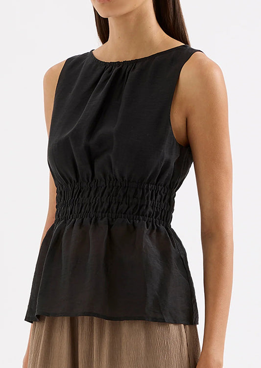 Black sleeveless top worn by a model on a white background