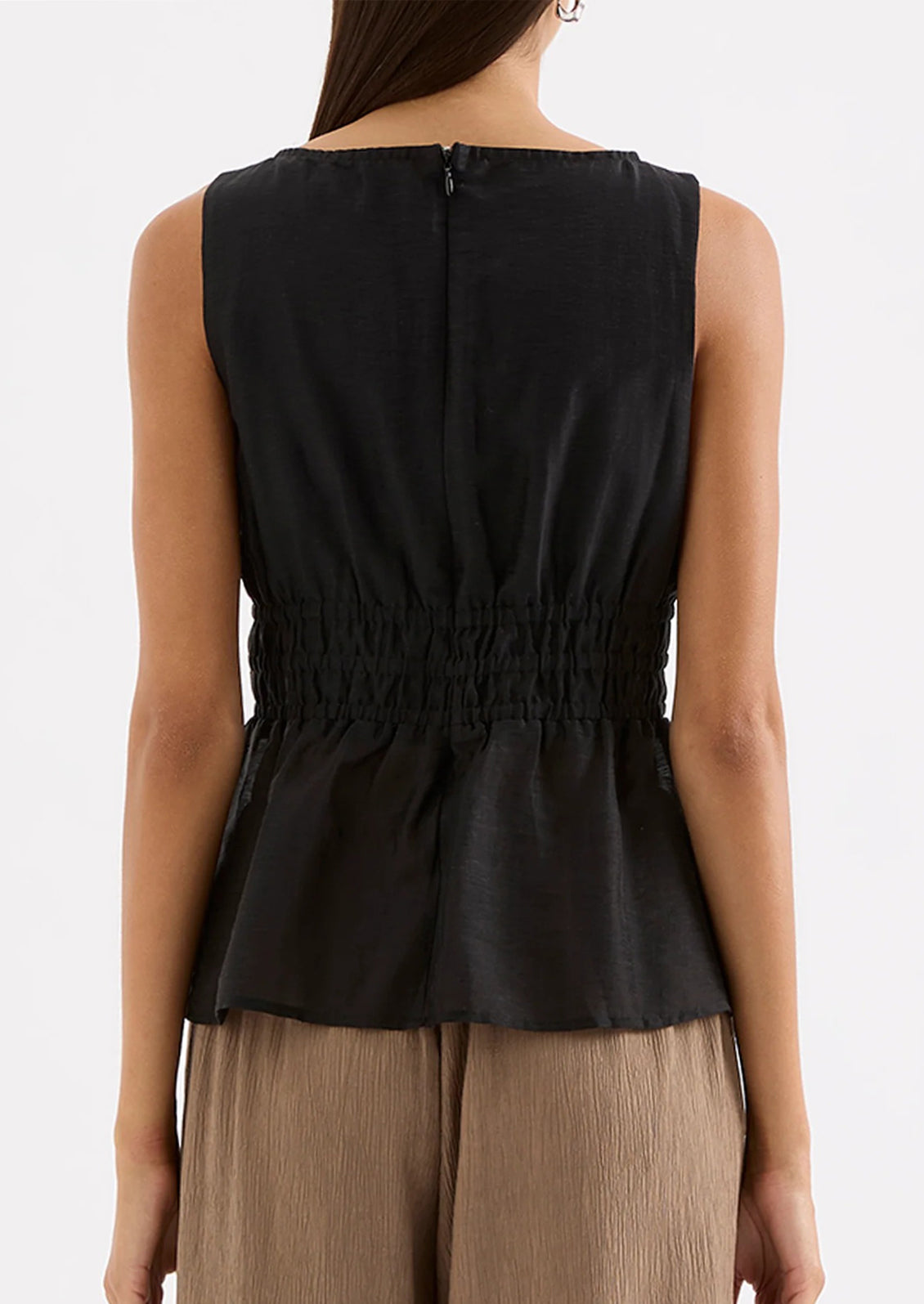 Black sleeveless top worn by a person on a white background