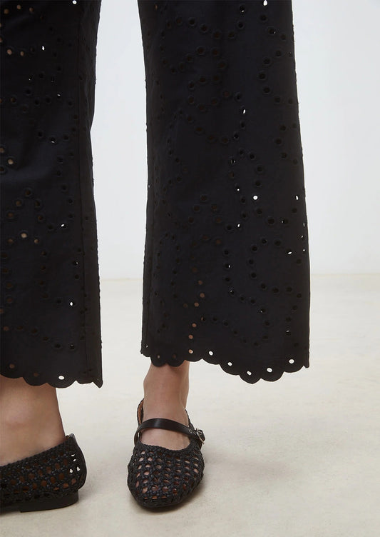 Black pants with cut-out details and black shoes on a white background