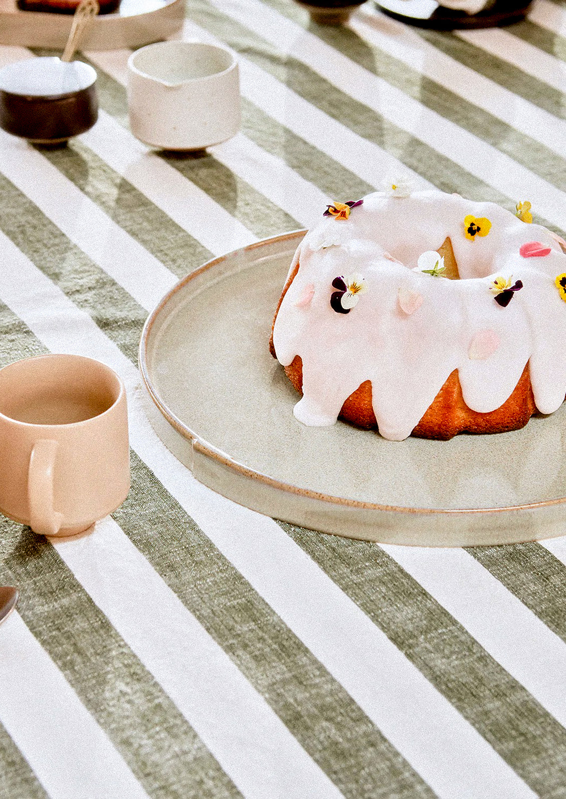 A cotton tablecloth in green and white stripe pattern.