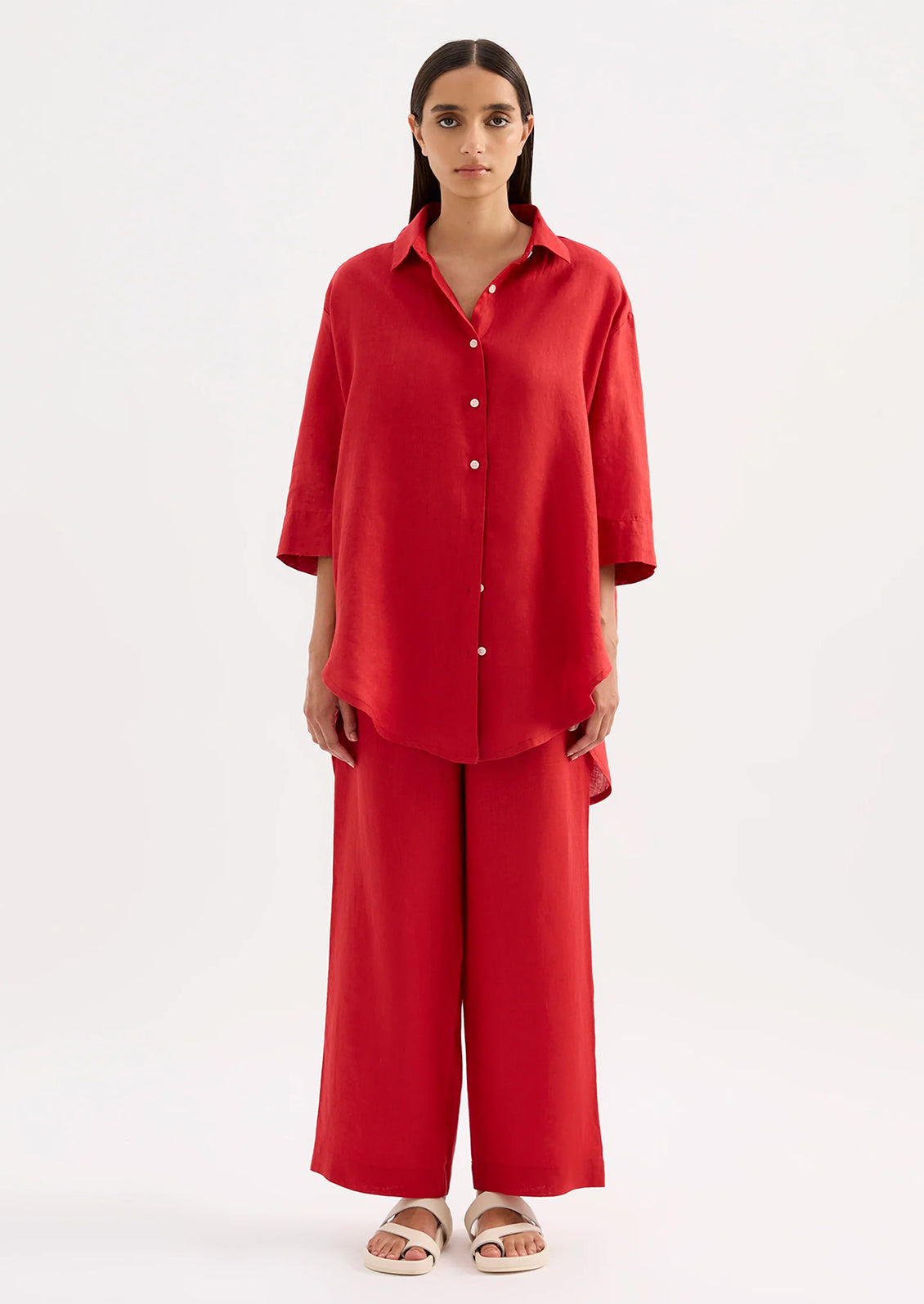 A woman wearing a relaxed red linen shirt.