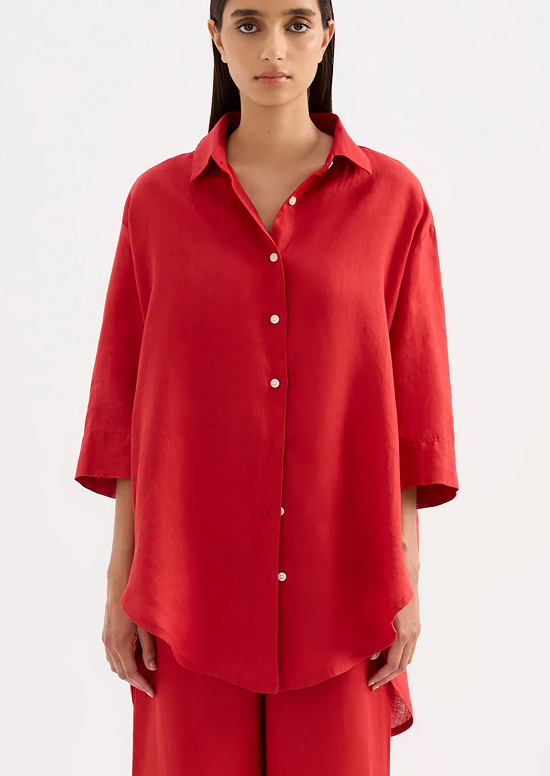 A woman wearing a relaxed red linen shirt.