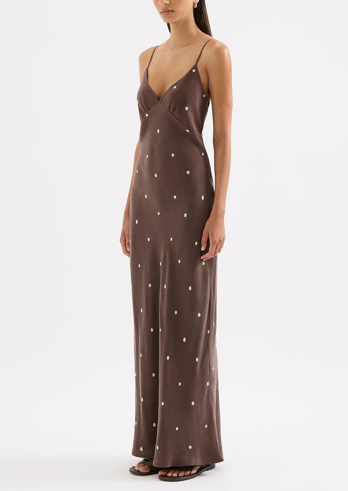 Woman wearing a brown slip dress with white polka dots on a white background