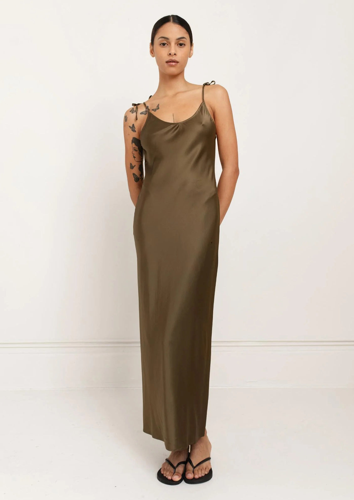 A person wearing a long slinky tank dress in olive green.