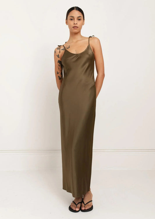 A person wearing a long slinky tank dress in olive green.