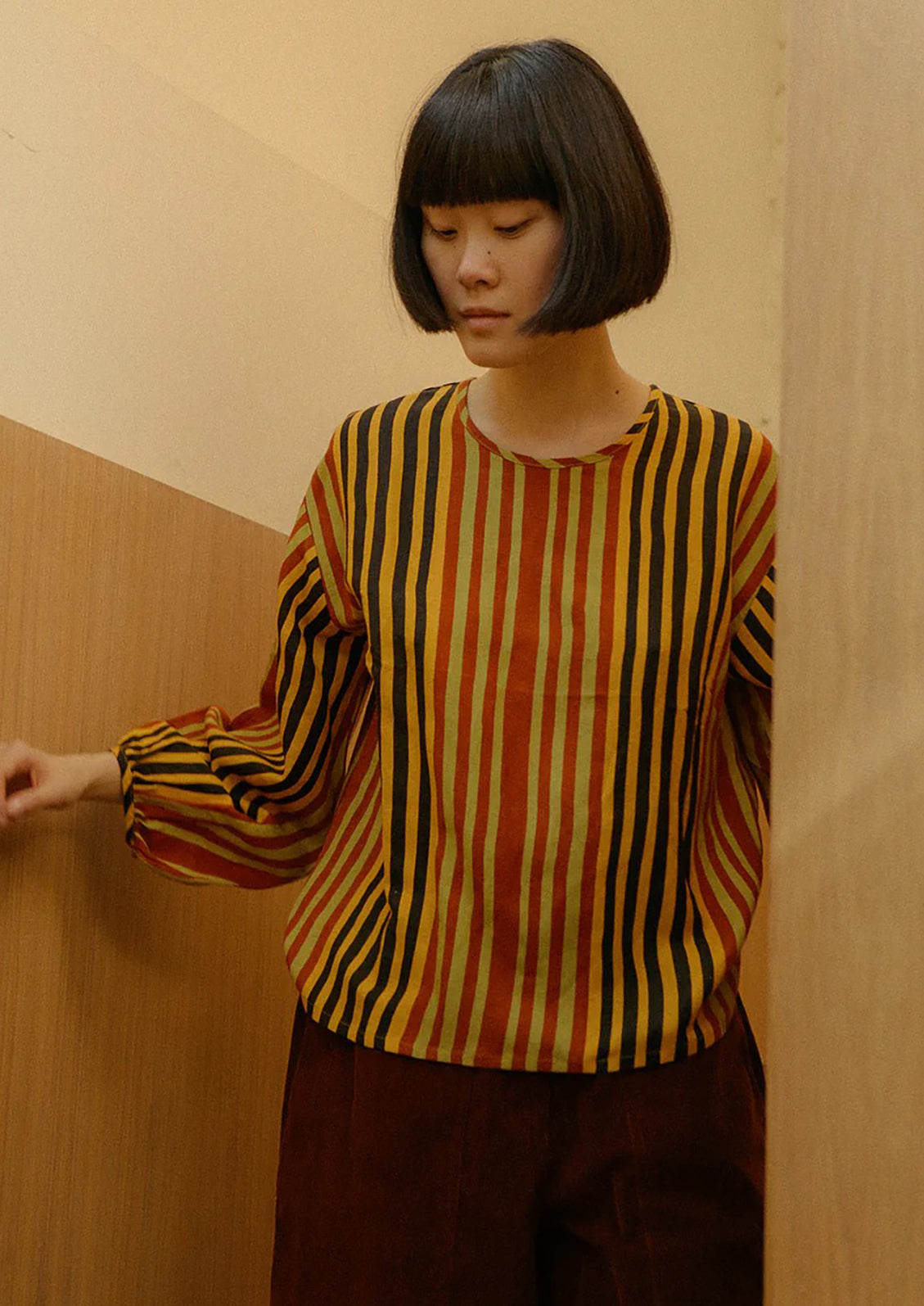 Person wearing a striped shirt with a warm-toned background