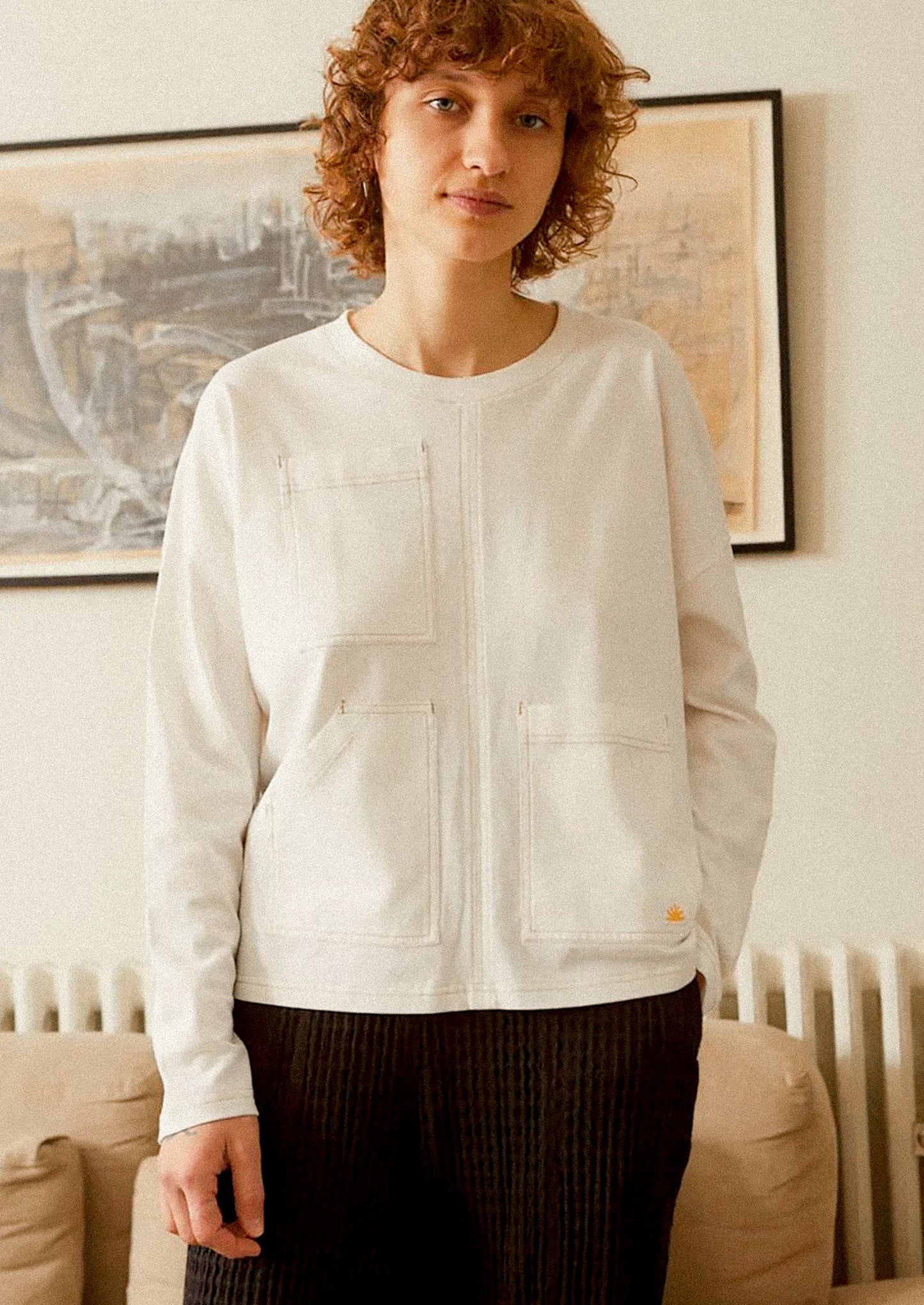 Person wearing a white long sleeve t-shirt in a living room setting