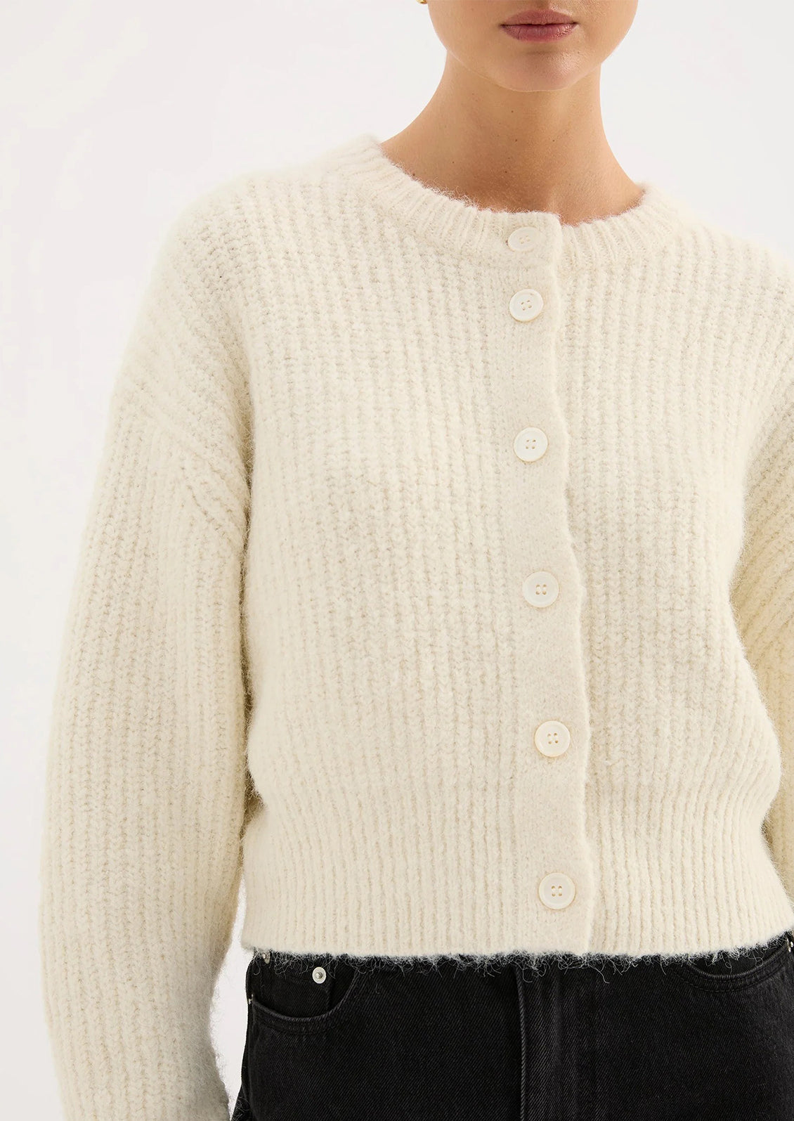 Close-up of a person wearing a cream-colored cardigan against a white background