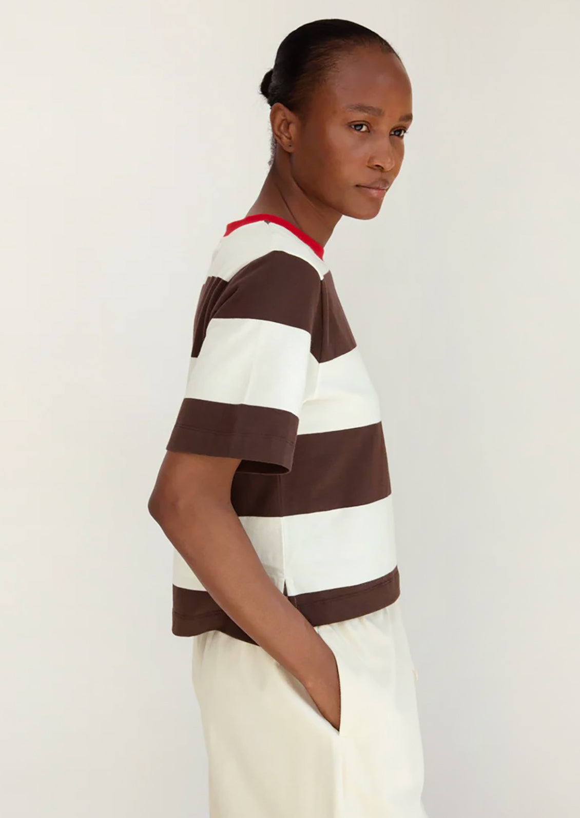 Person wearing a brown and white striped shirt against a plain background
