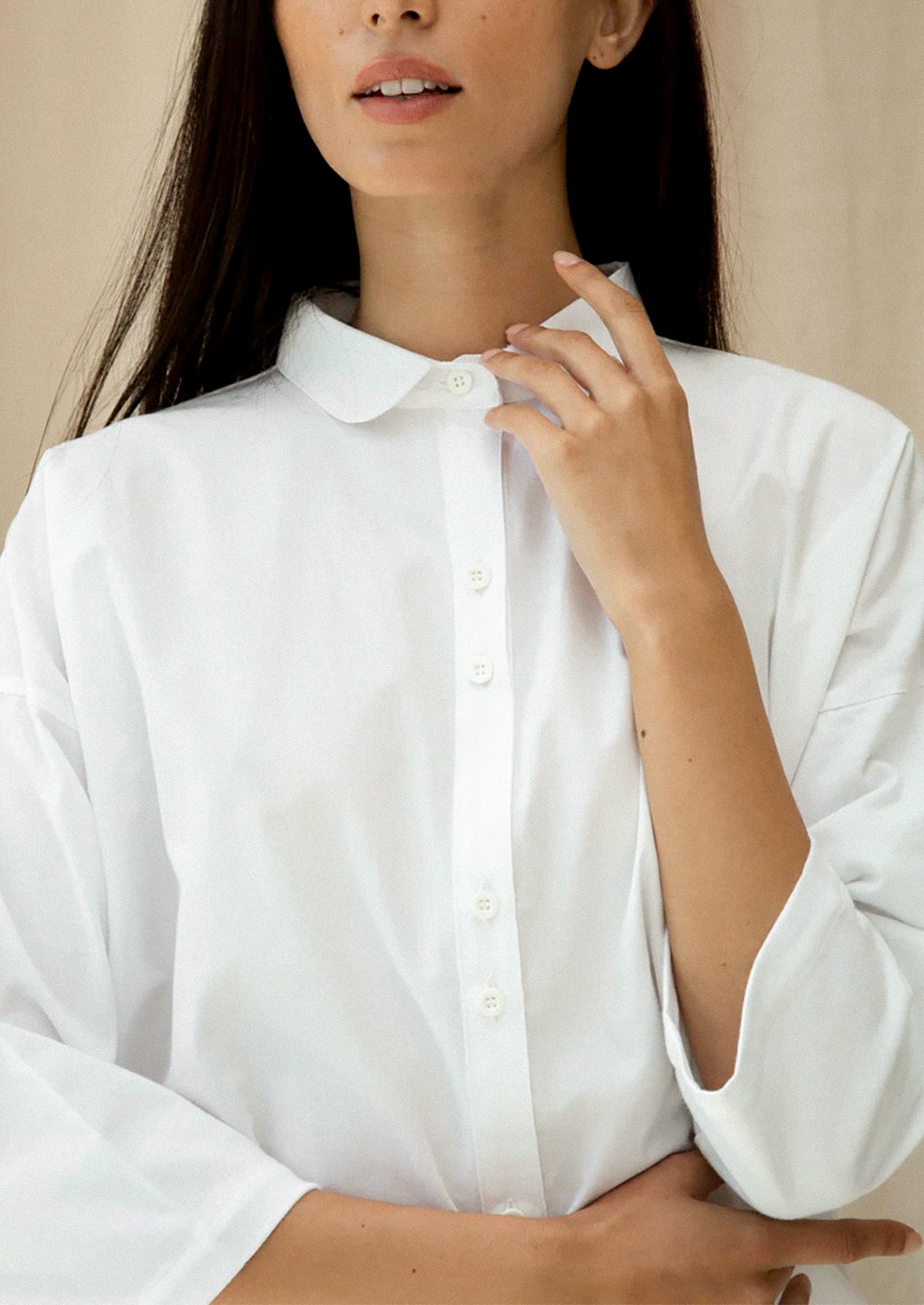 Person wearing a white shirt against a neutral background