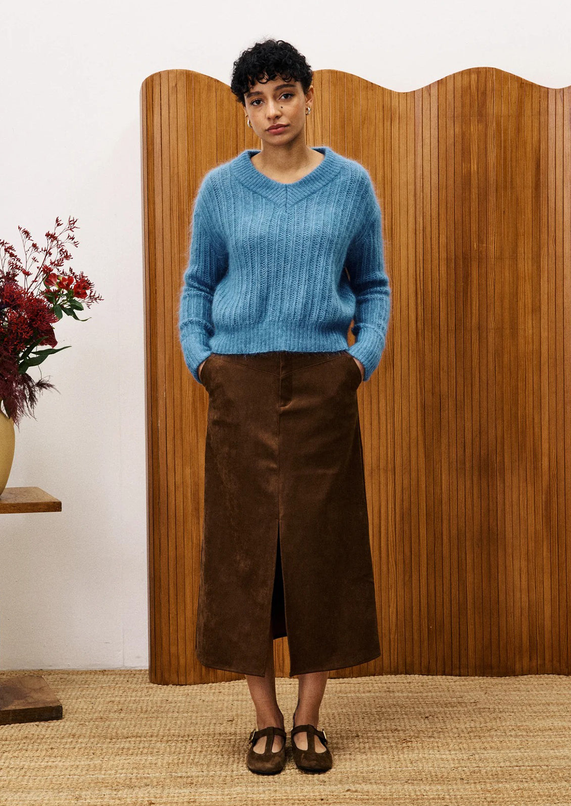 A woman wearing a dusty blue v-neck sweater.