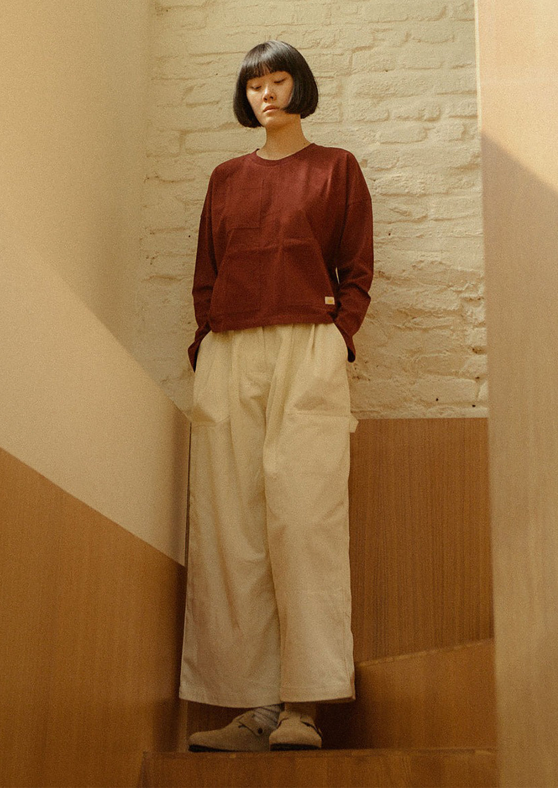 A person wearing a pair of workwear-inspired pants in ecru color.