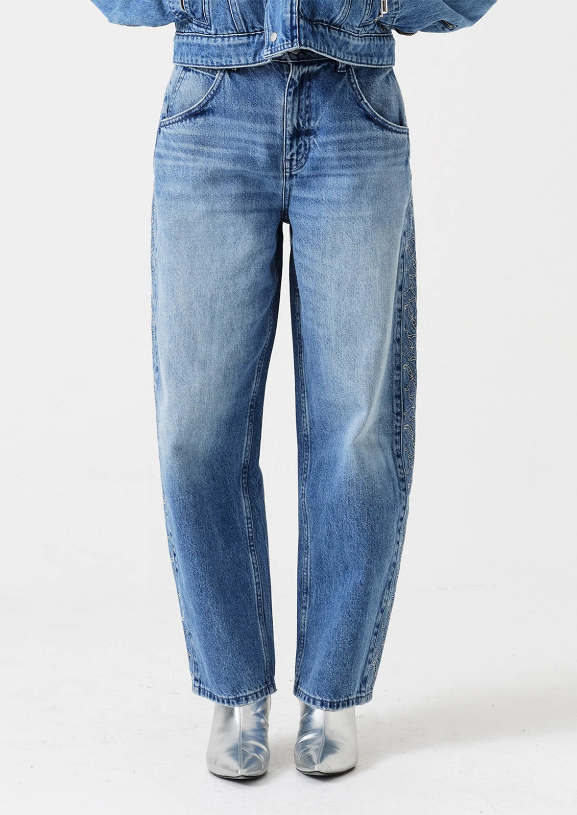 Person wearing blue jeans and a denim jacket on a white background