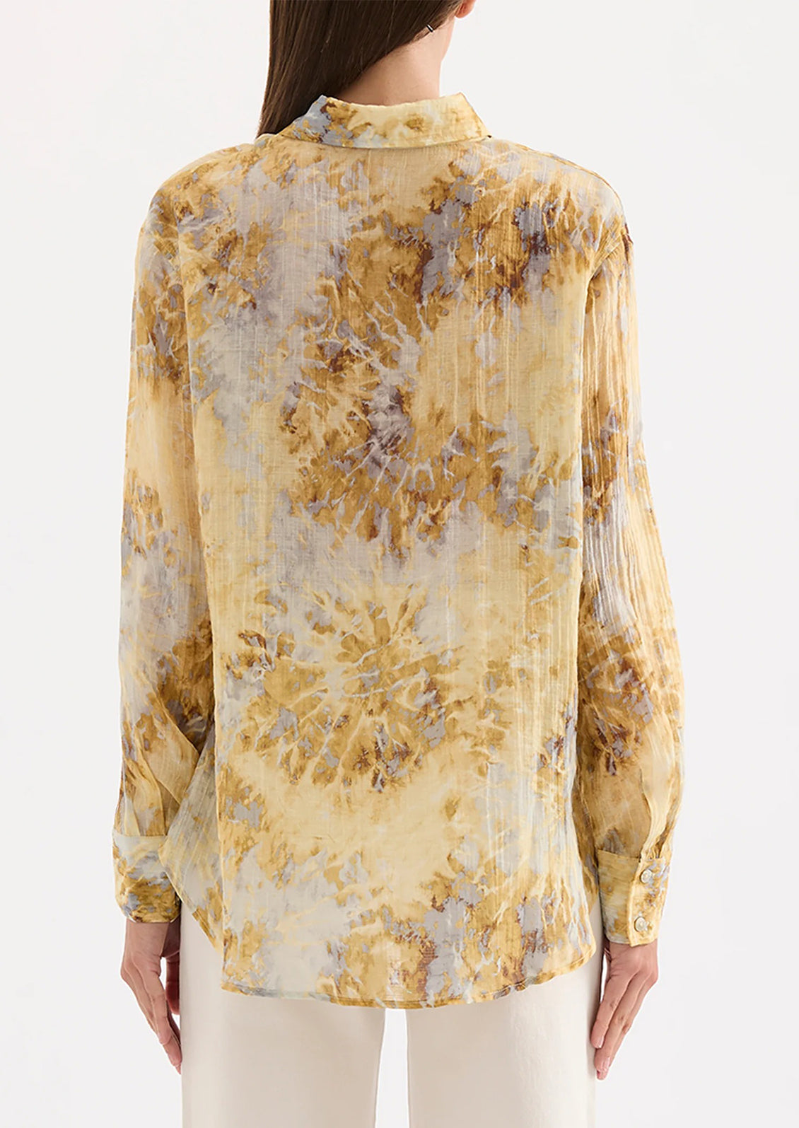 Woman wearing a yellow tie dye blouse against a white background