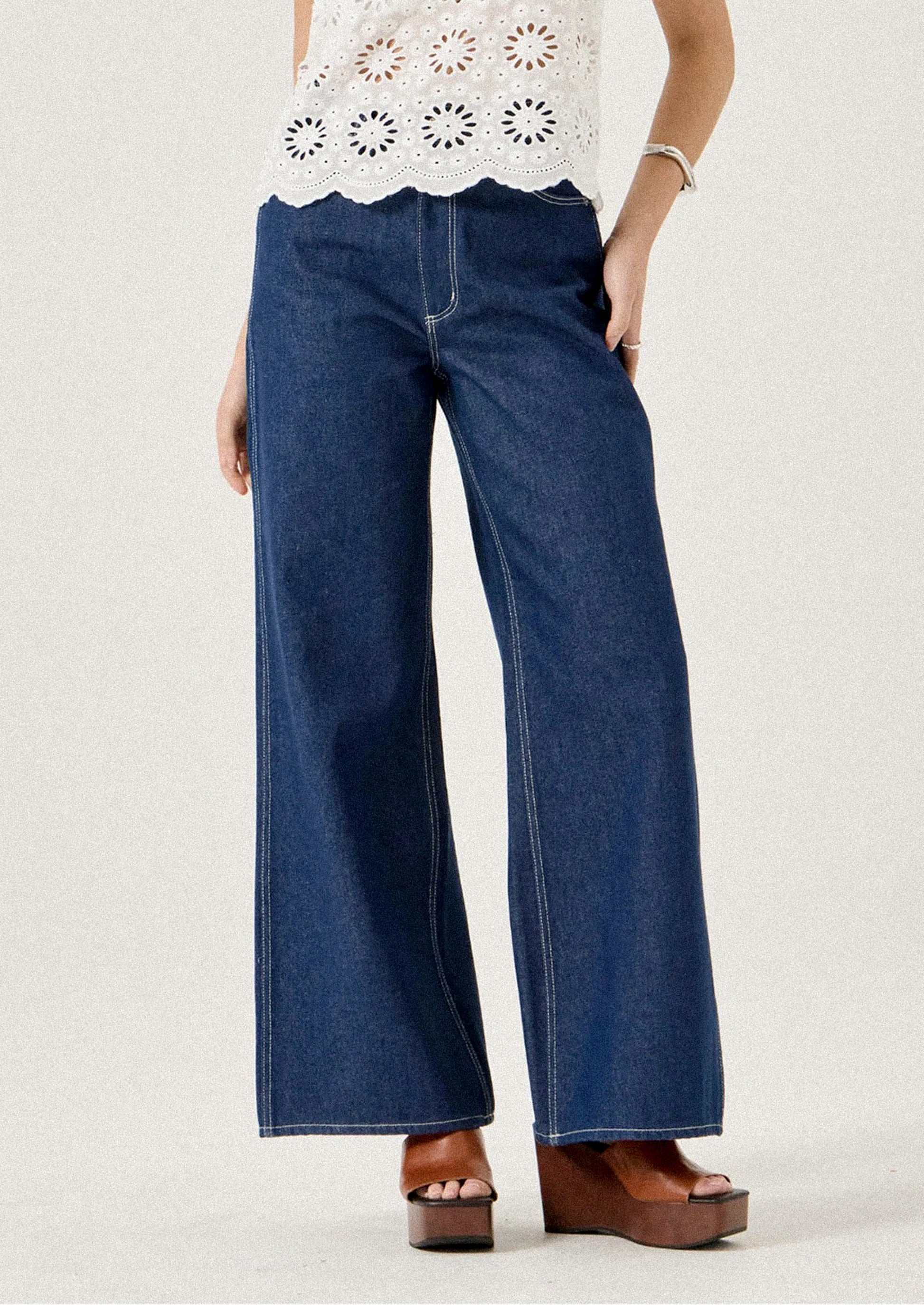 Person wearing blue wide-leg jeans on a plain background