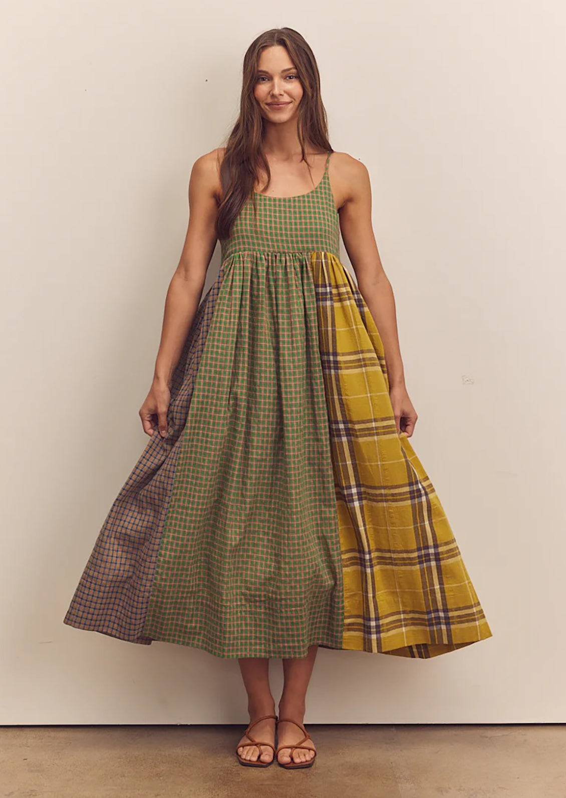 A person wearing a long tank dress in mixed color plaid pattern.