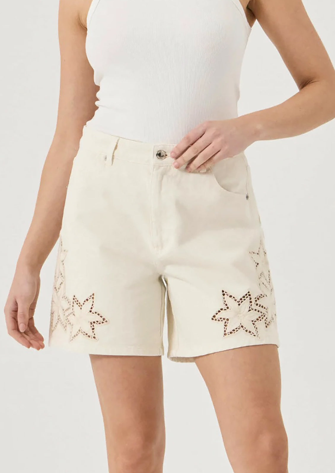 Beige shorts with star patterns worn by a person on a plain background