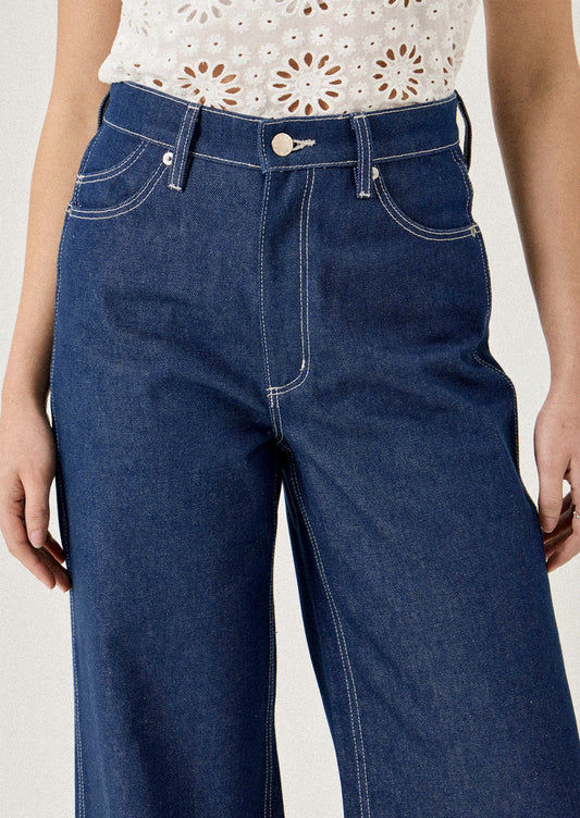 Person wearing blue jeans on a plain background