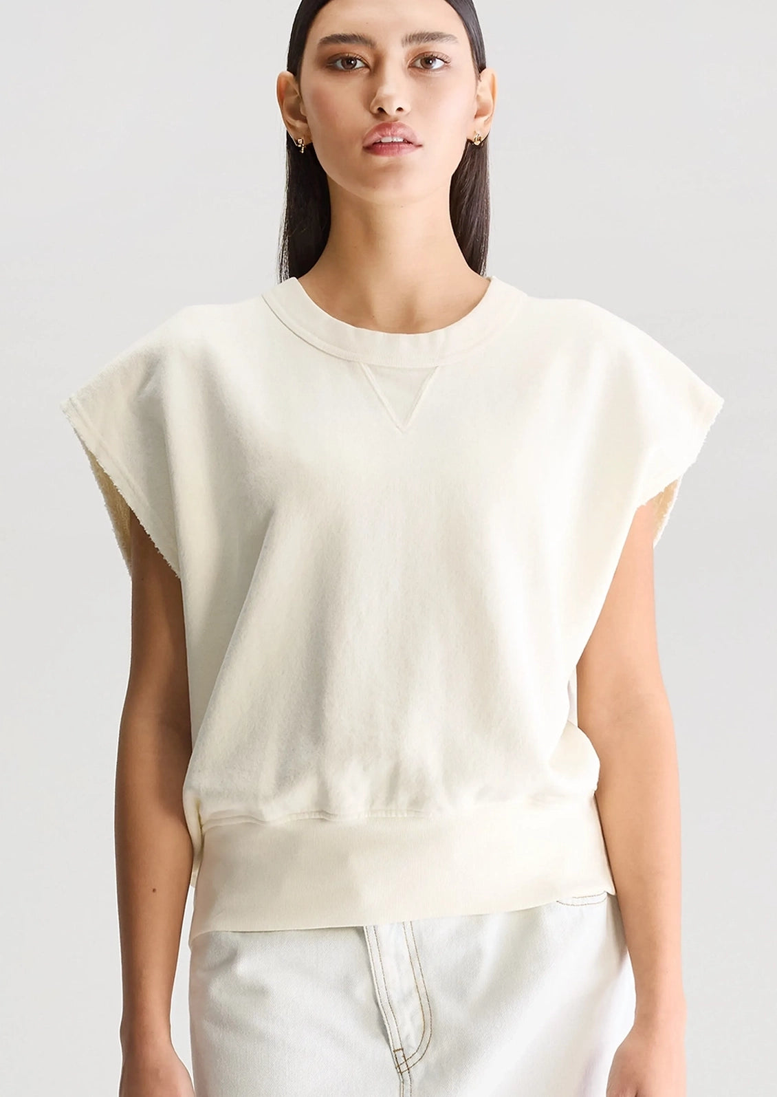 A woman wearing an ivory cut-off sweatshirt.