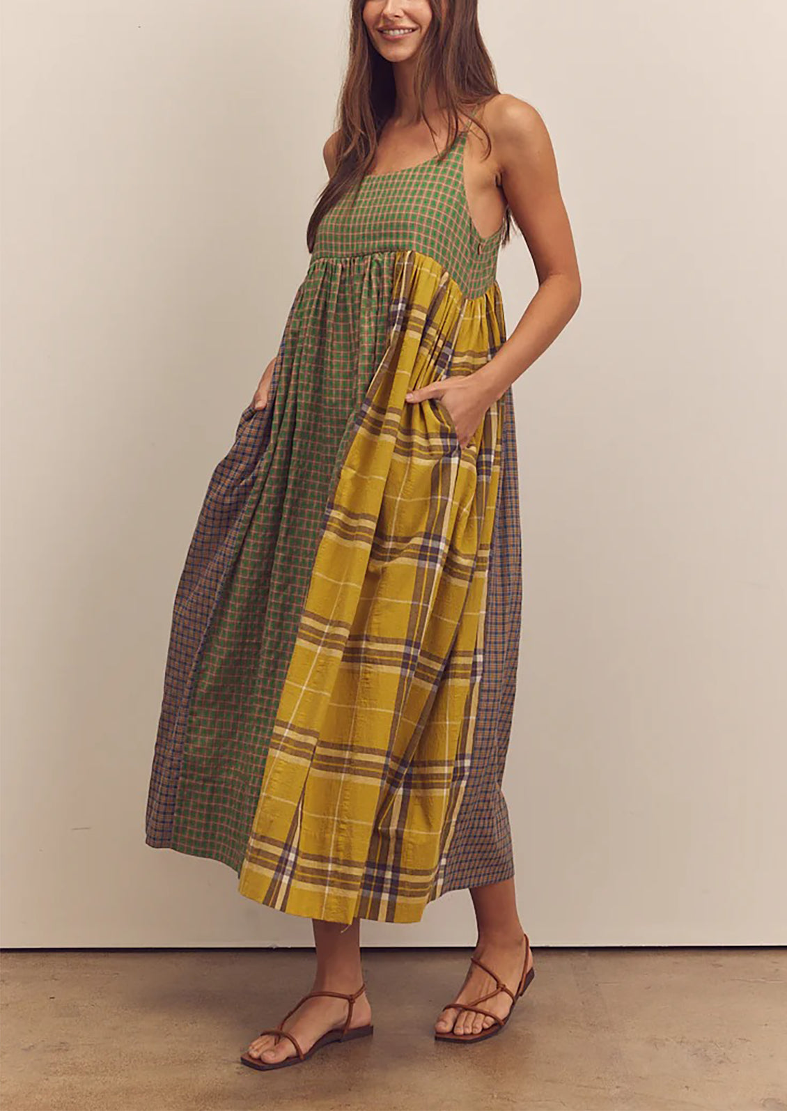 A person wearing a long tank dress in mixed color plaid pattern.
