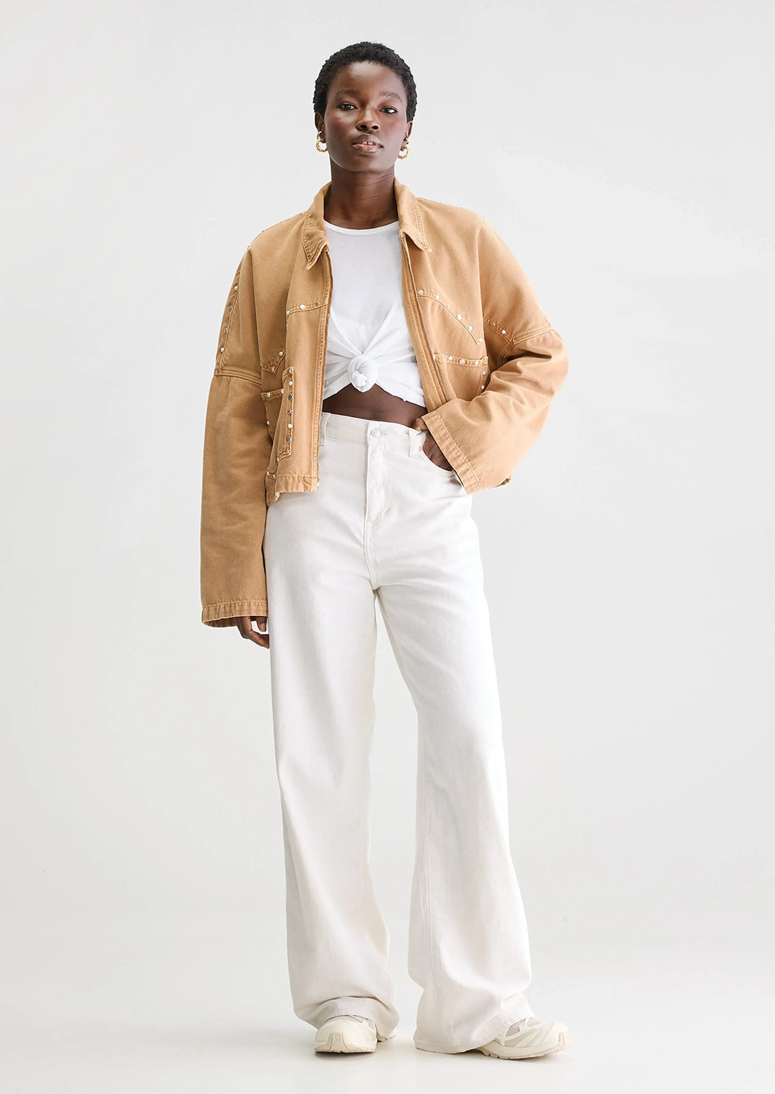 Person wearing a tan jacket with studded details.