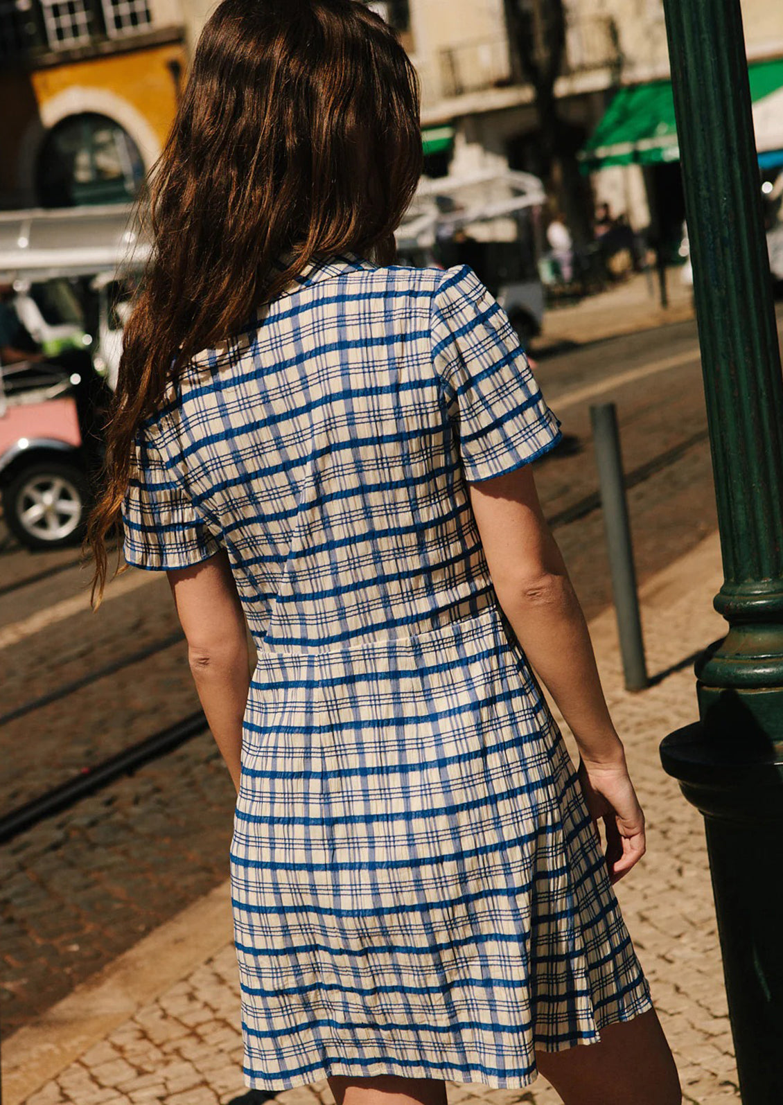 A blue and white plaid mini dress with primary colored floral embroidery at collar.