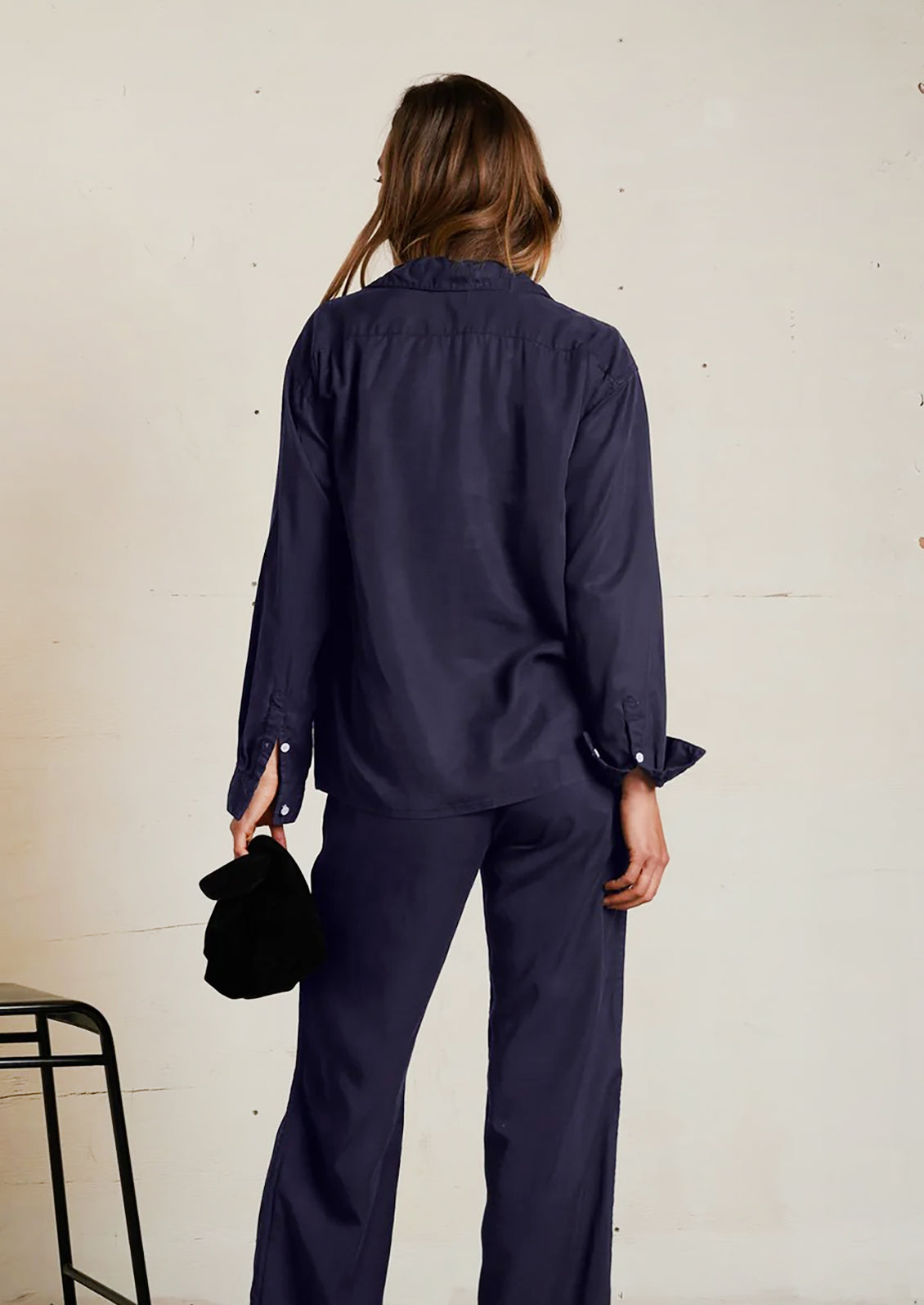 Person wearing a navy blue outfit with a plain background