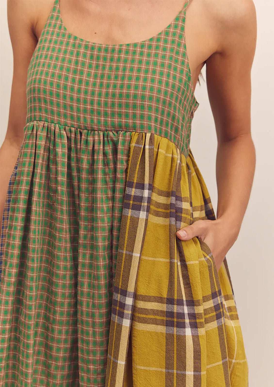 A person wearing a long tank dress in mixed color plaid pattern.