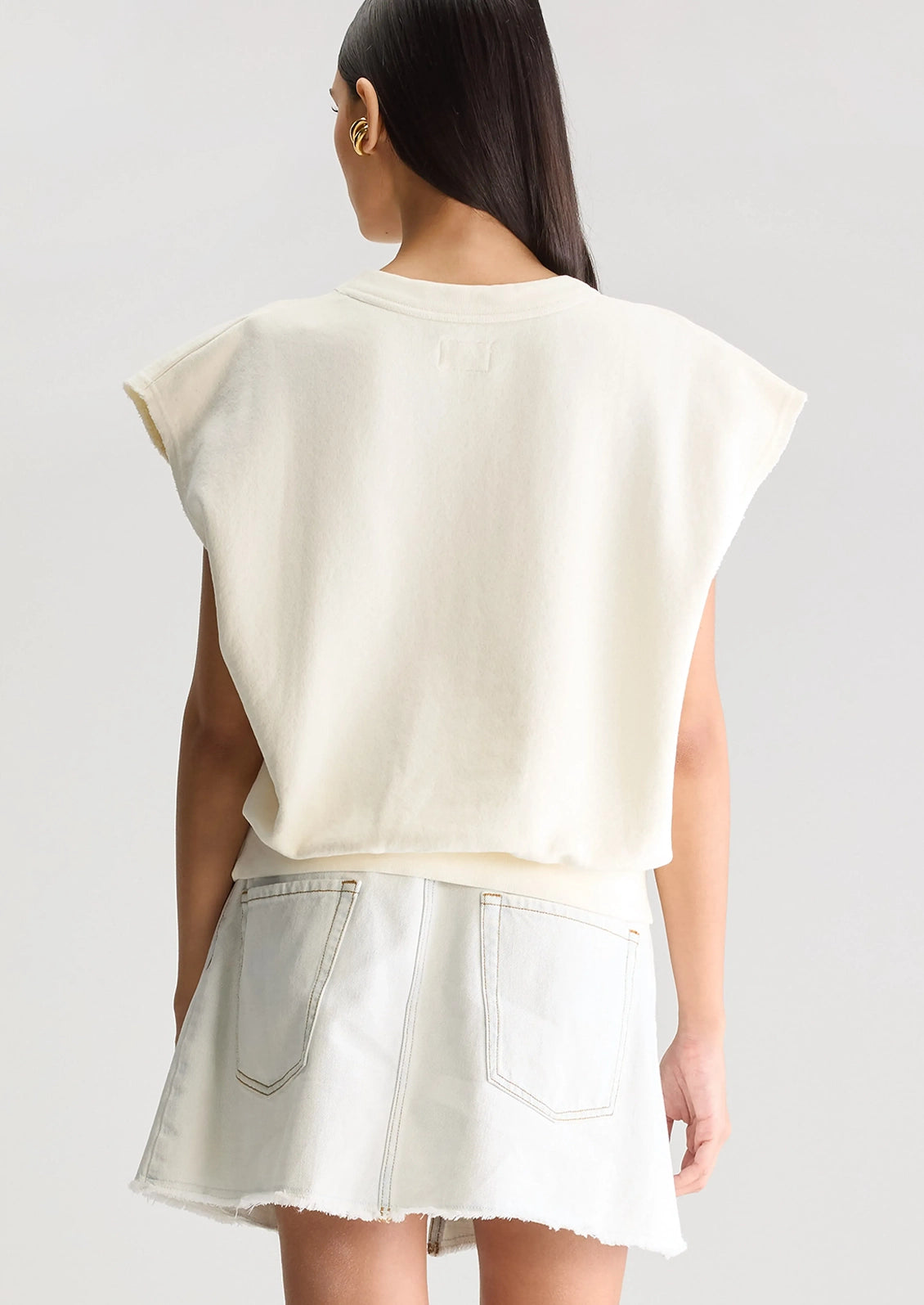 A woman wearing an ivory cut-off sweatshirt.