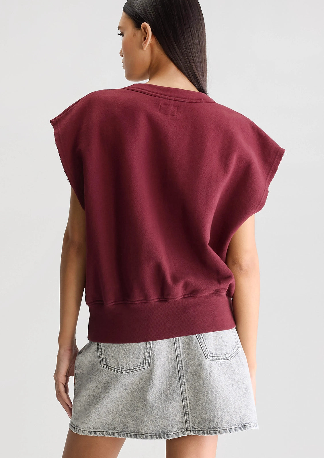 A woman wearing a burgundy cut-off sweatshirt.
