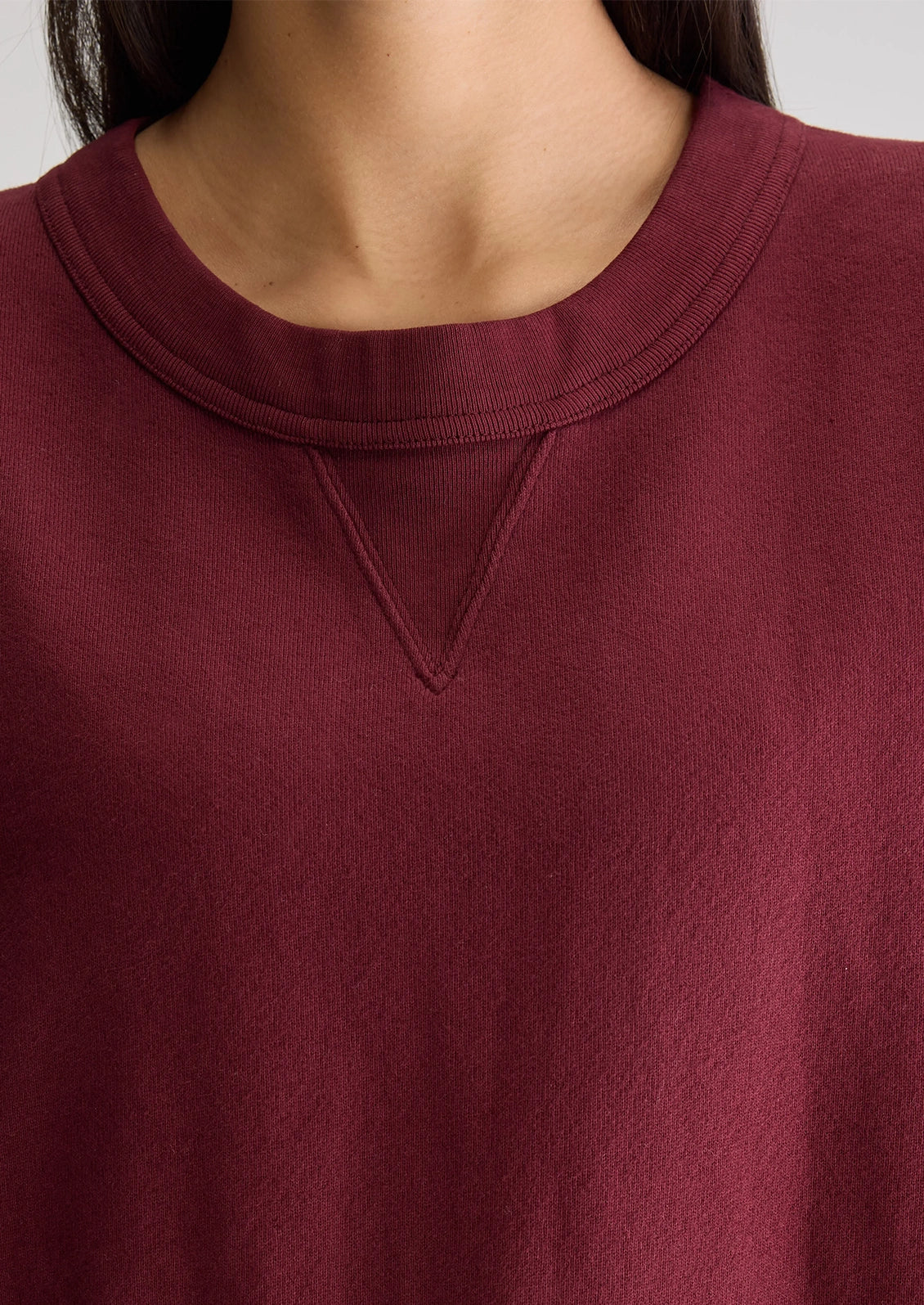 A woman wearing an burgundy cut-off sweatshirt.