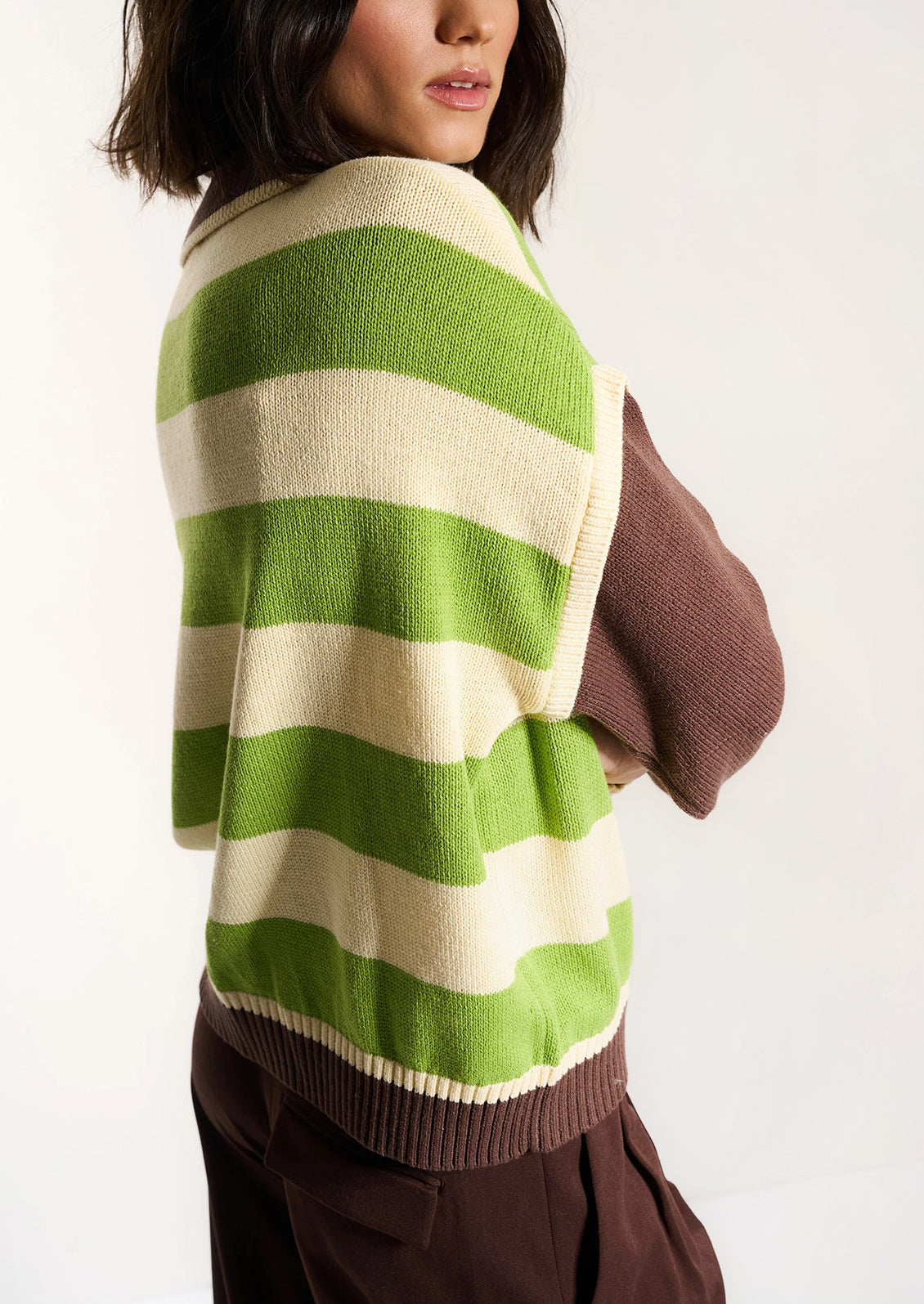 Person wearing a green and white striped sweater with a brown background