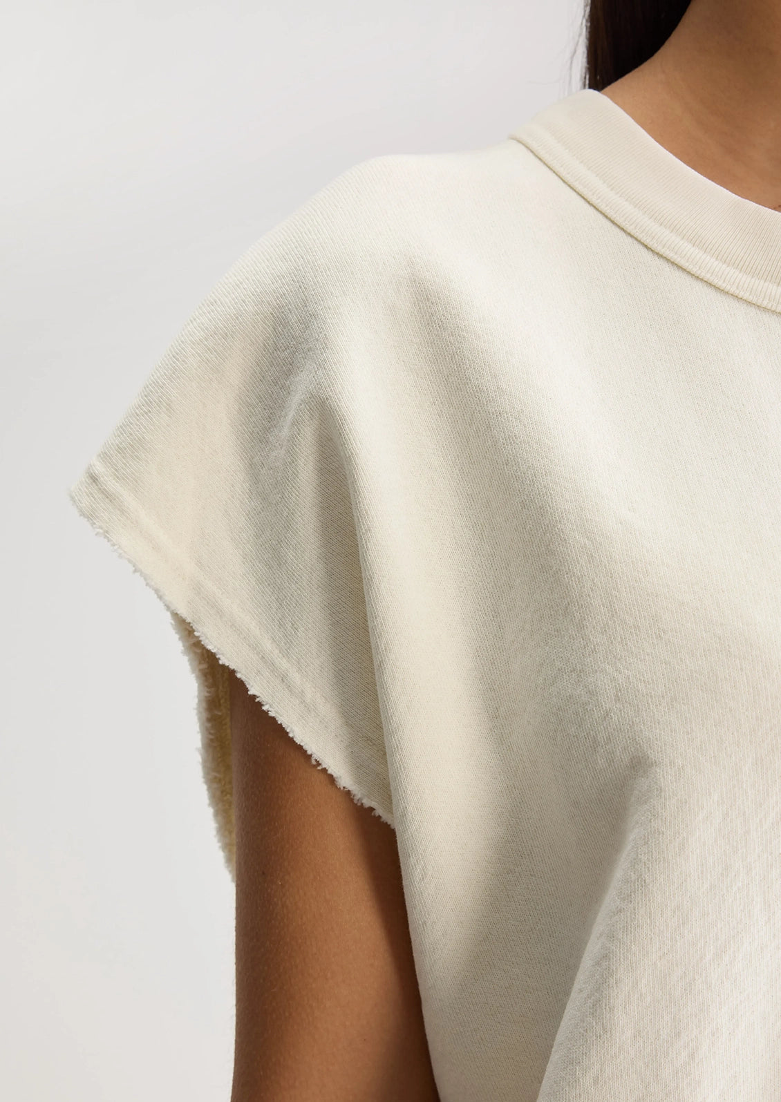 A woman wearing an ivory cut-off sweatshirt.