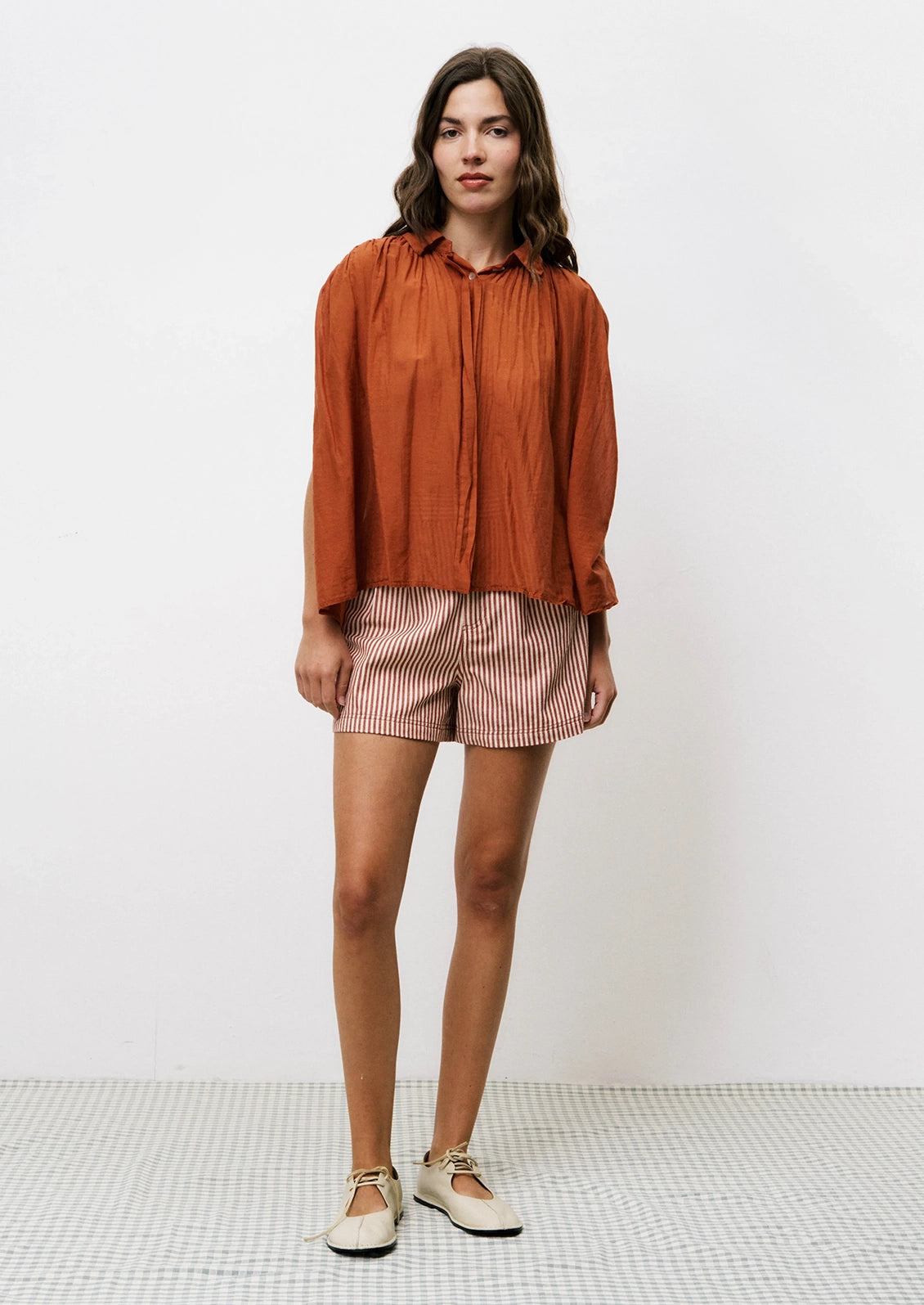 A pair of shorts in cream and rust vertical stripe pattern.