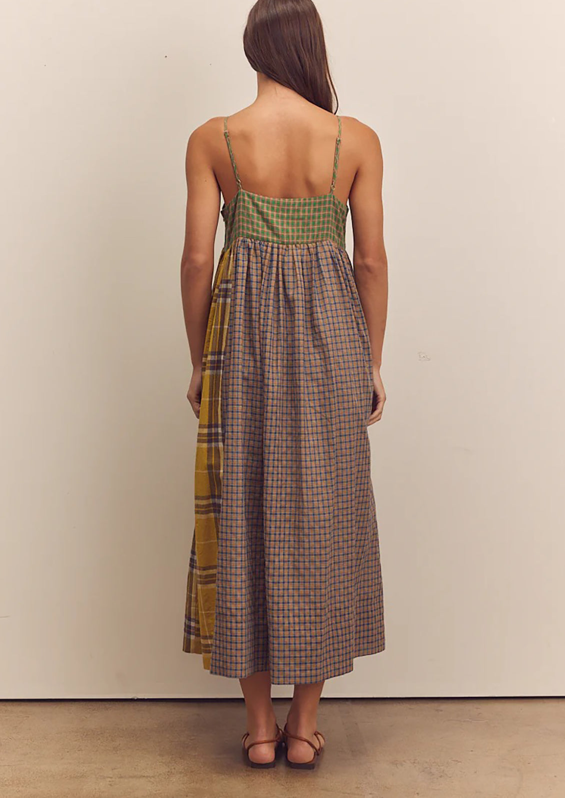 A person wearing a long tank dress in mixed color plaid pattern.
