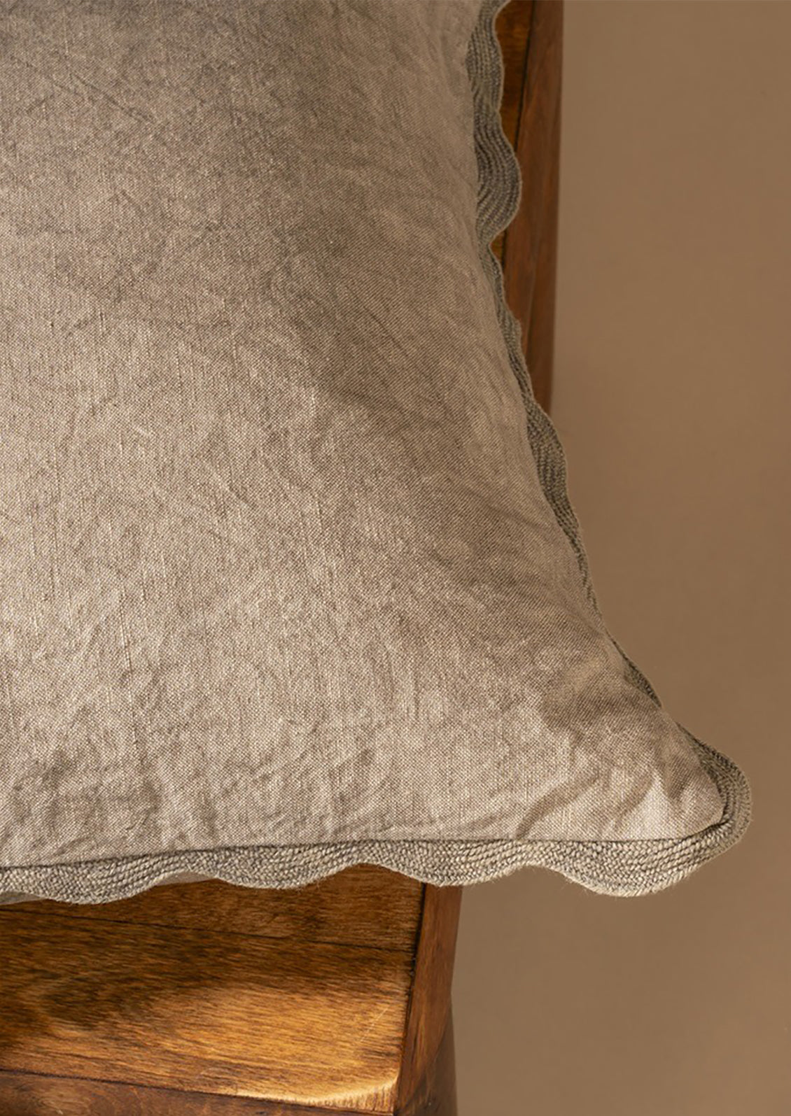Textured beige pillow on a wooden surface with a neutral background