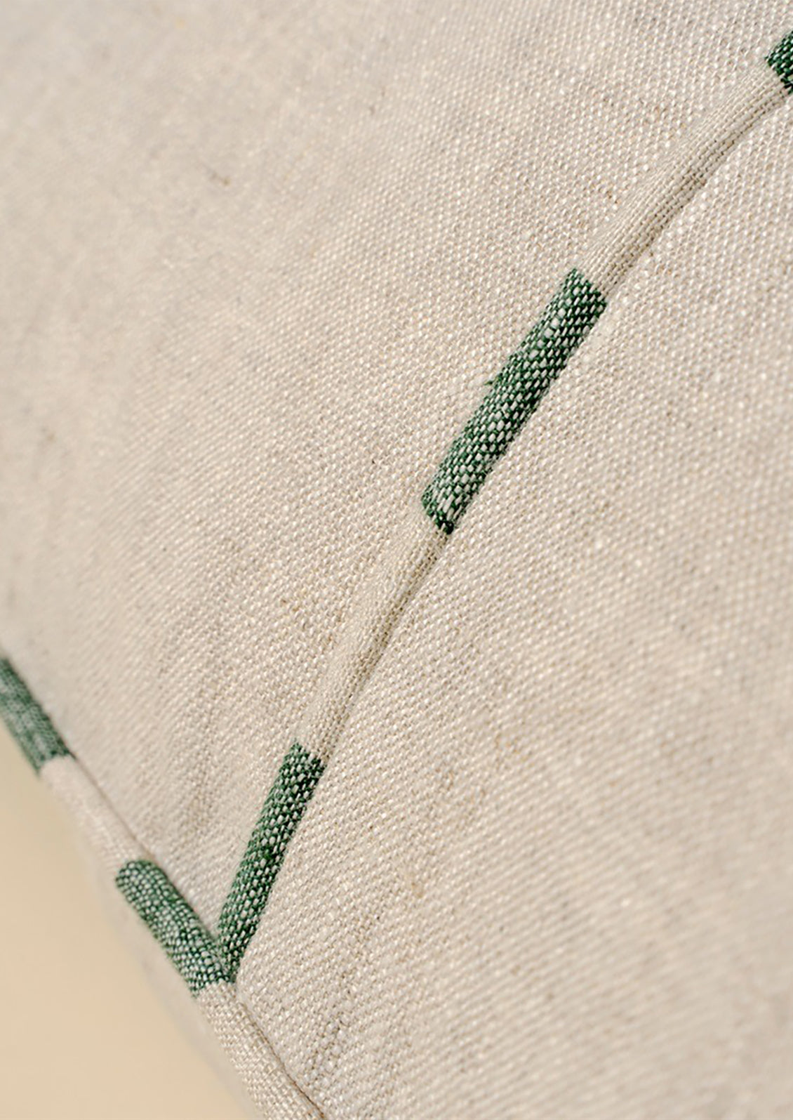 Close-up of natural linen pillow with green piping.