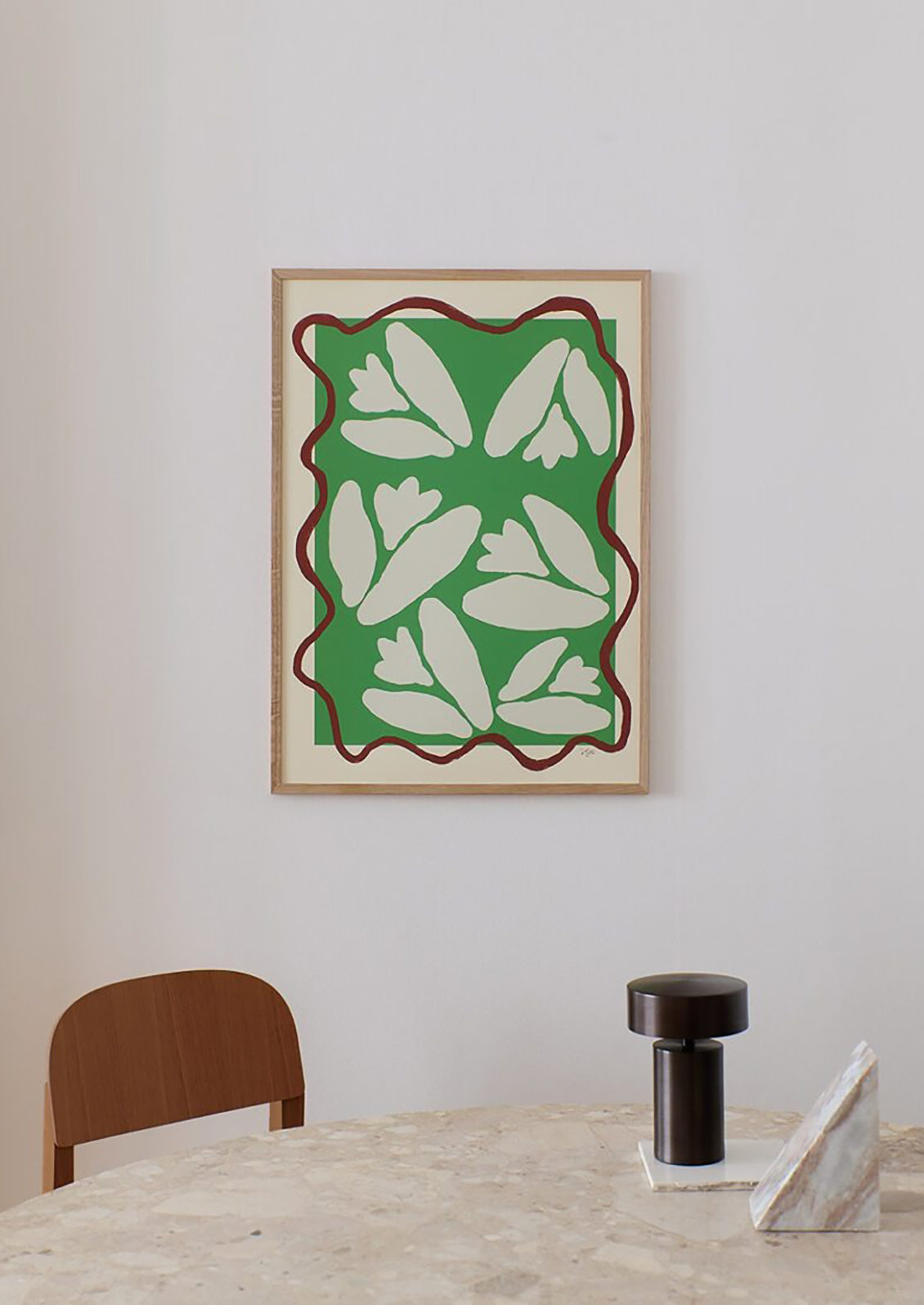 An art print on cream background with squiggly maroon frame around abstract lily of the valley flowers on green.