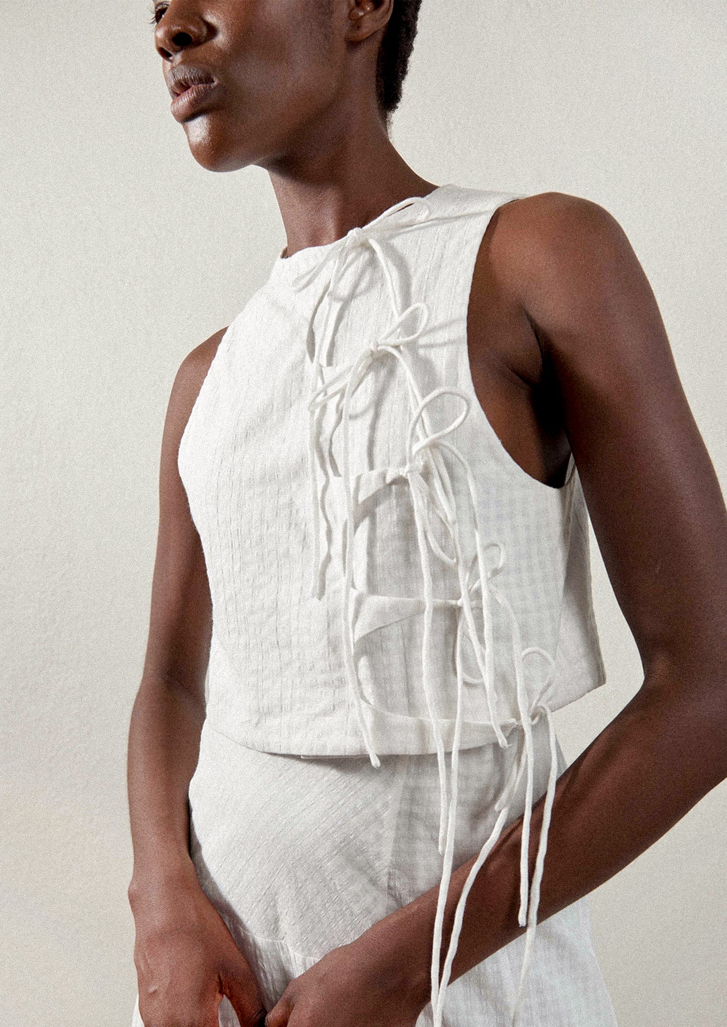 A woman wearing a tie front blouse in white tonal gingham fabric.
