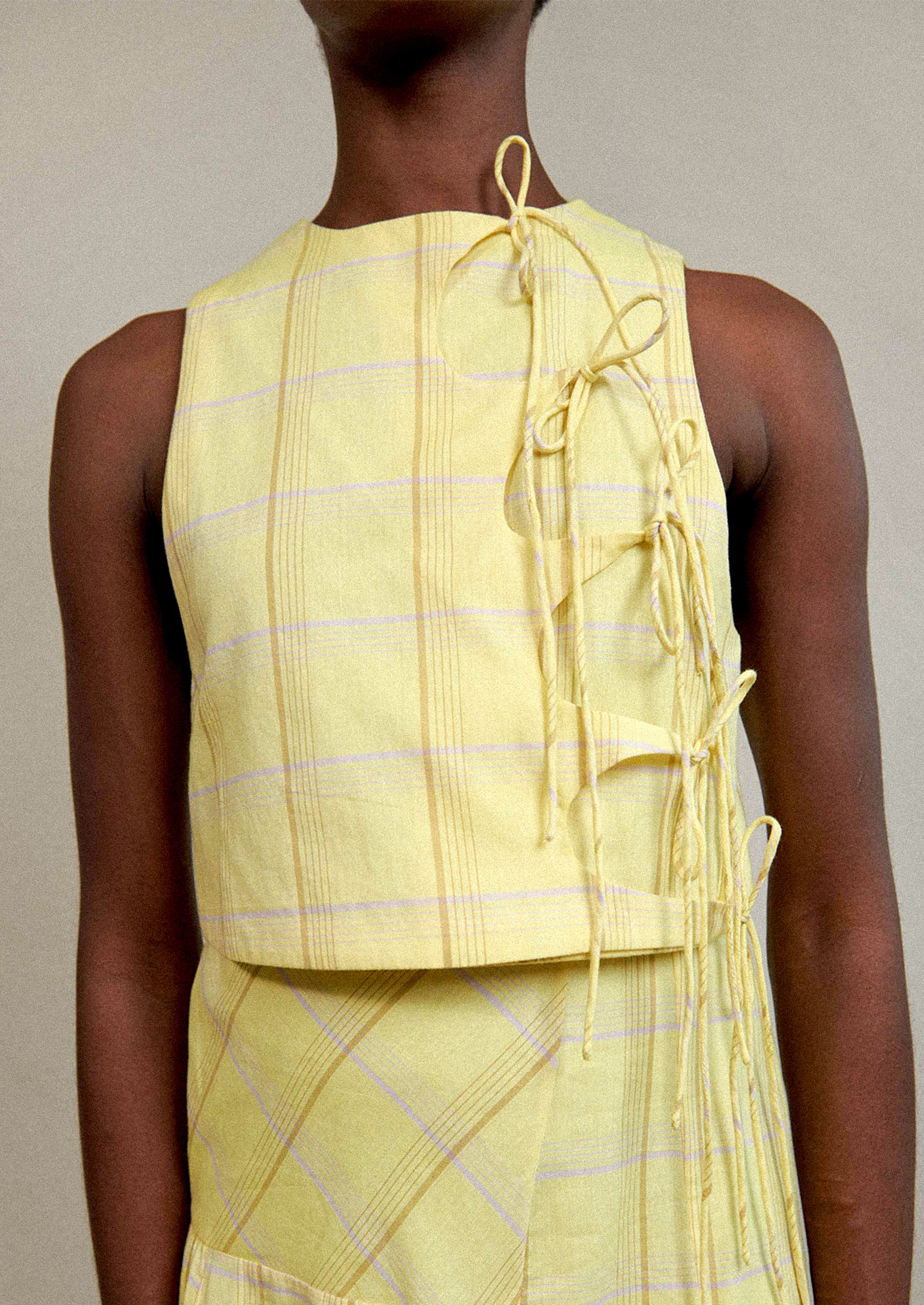 A woman wearing a tie front blouse in yellow plaid fabric.