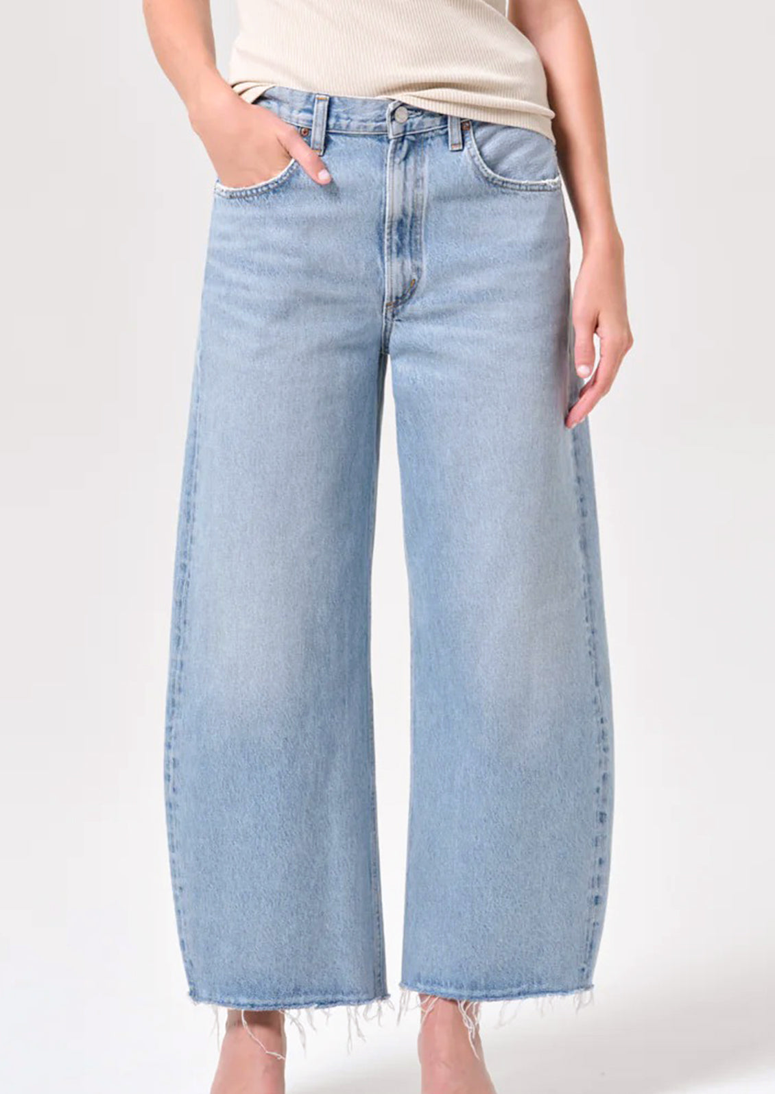 A person wearing a pair of light wash jeans with raw cut off hem.