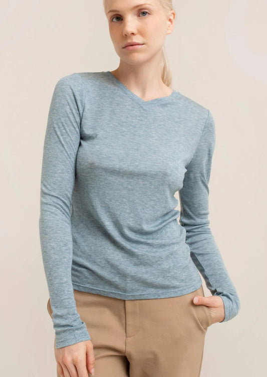 Woman wearing a blue long-sleeve top against a beige background