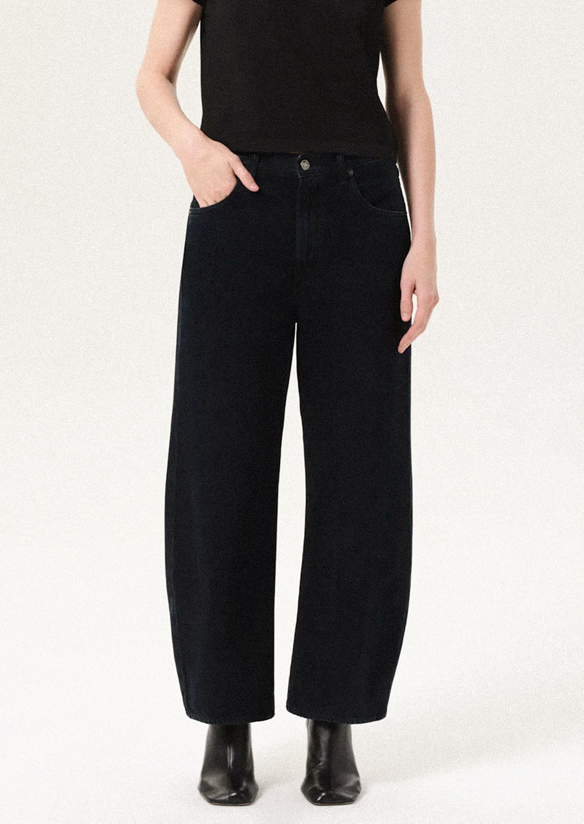 Person wearing black wide-leg jeans on a white background