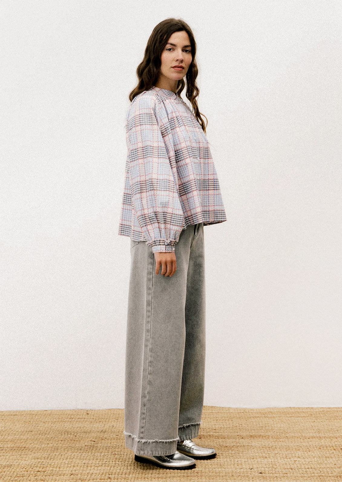 A person wearing a long sleeve blouse with blue and red plaid pattern.