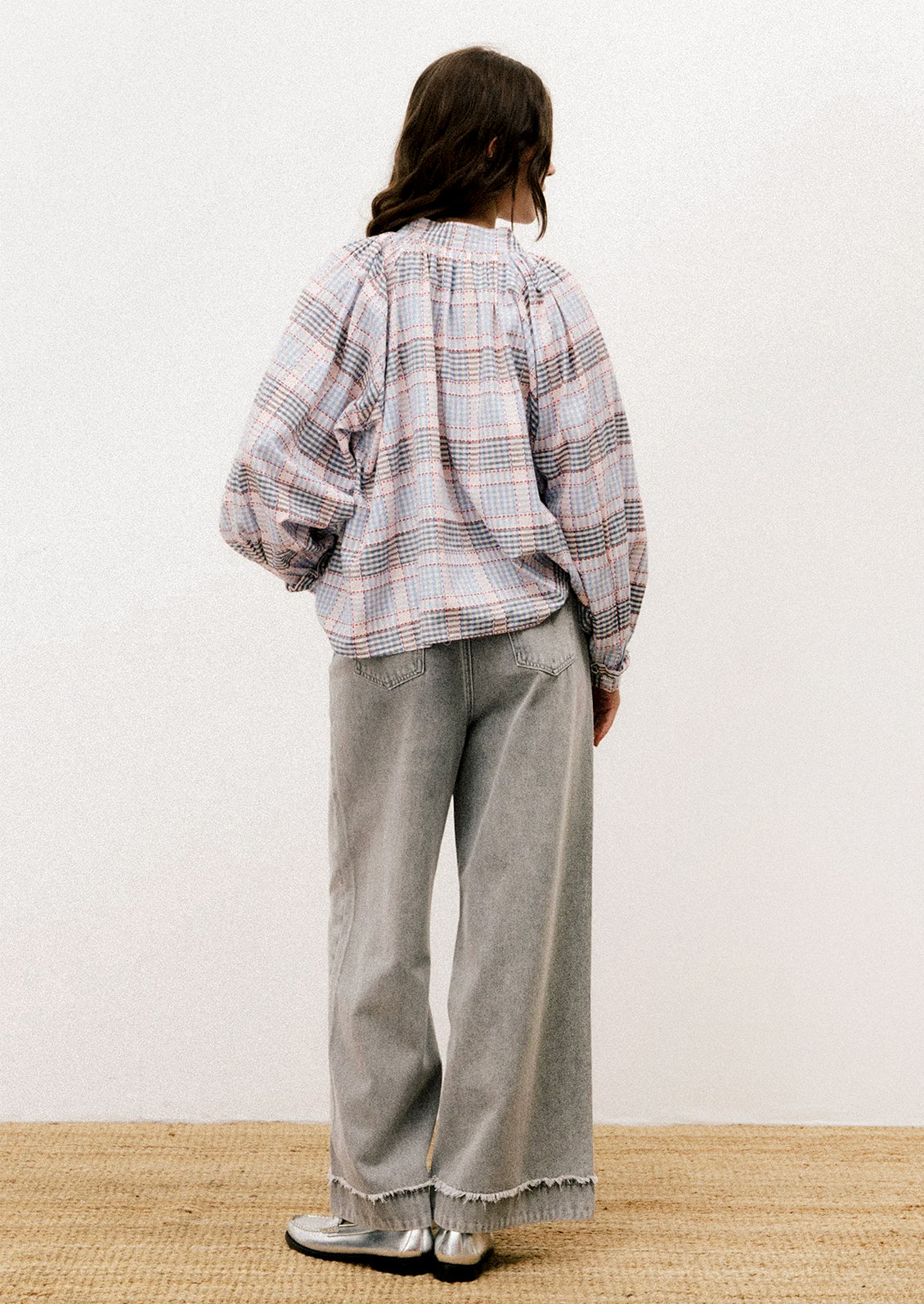 A person wearing a long sleeve blouse with blue and red plaid pattern.