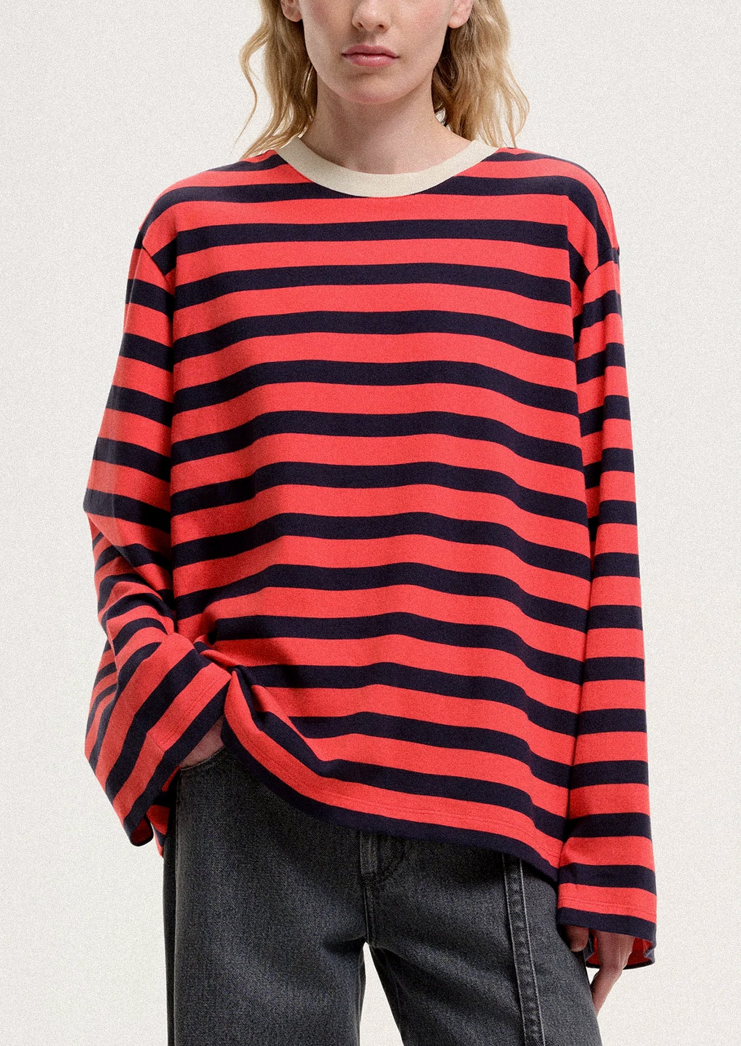 Person wearing a red and black striped sweater on a plain background