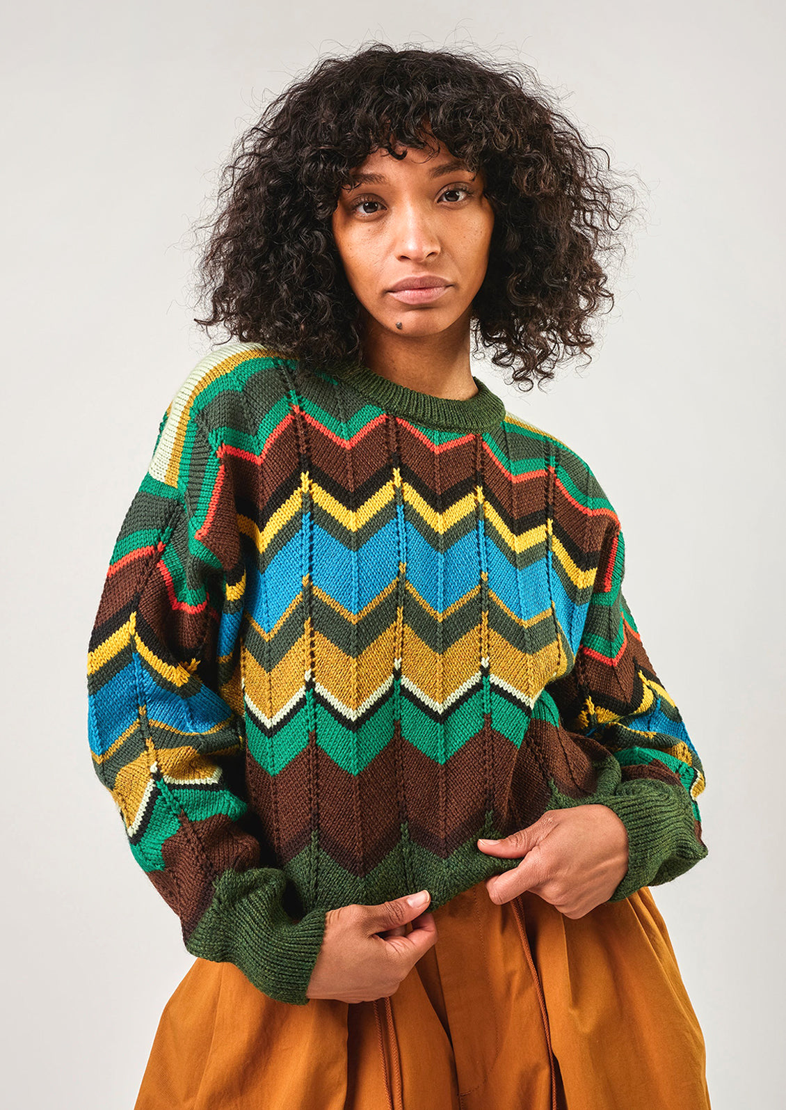 Person wearing a colorful patterned sweater against a plain background