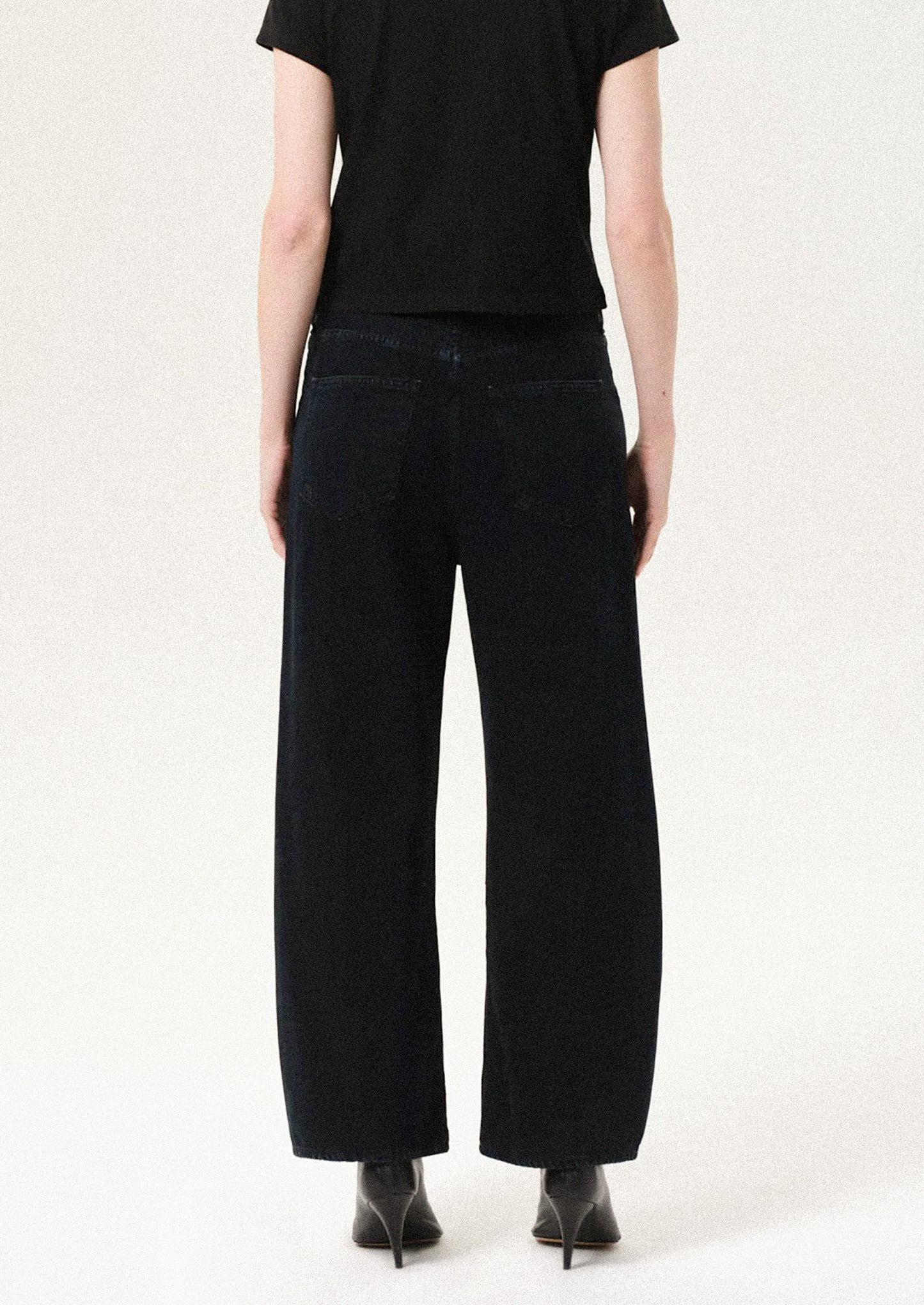 Person wearing black wide-leg pants and a black top on a white background