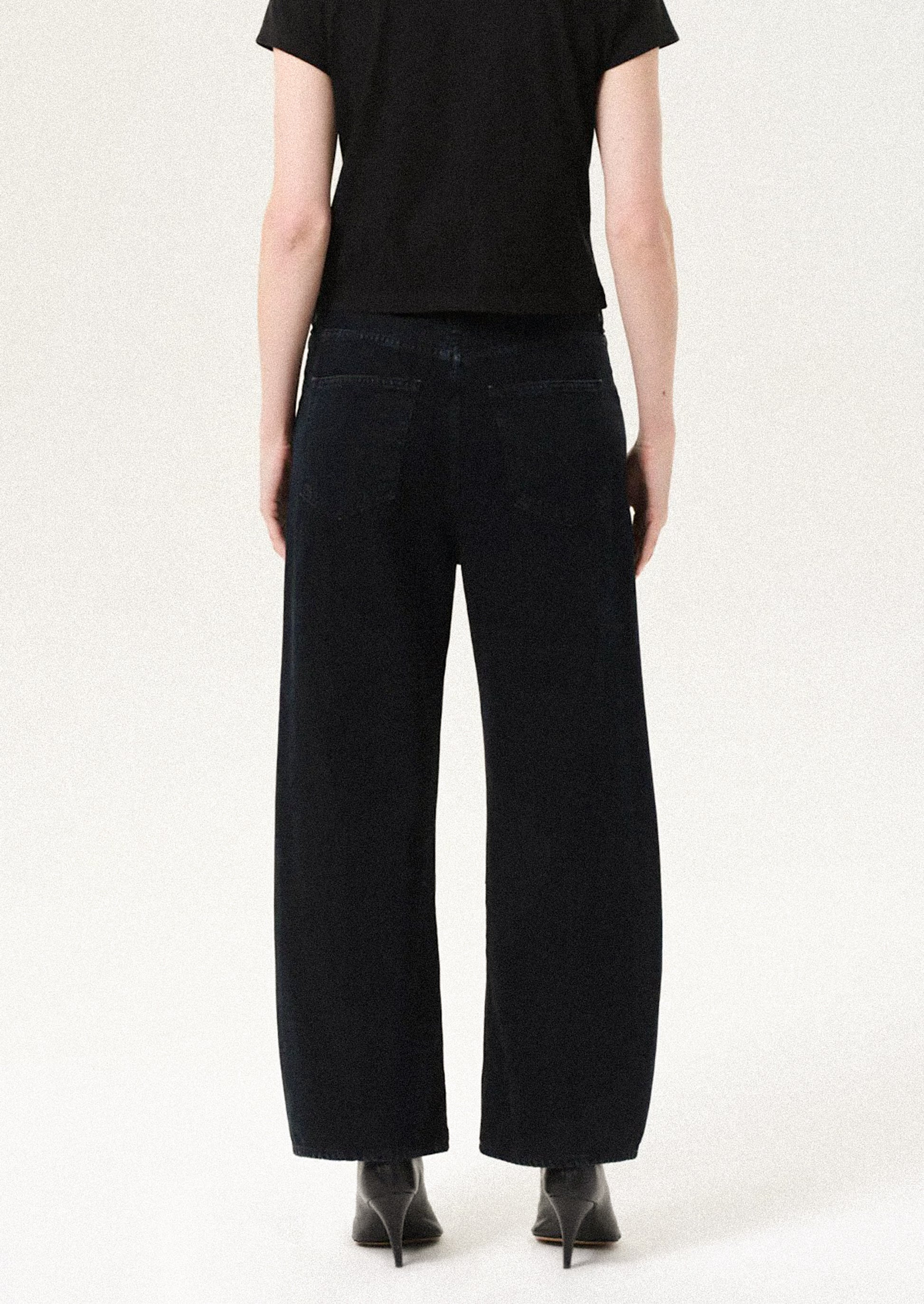 Person wearing black wide-leg pants and a black top on a white background